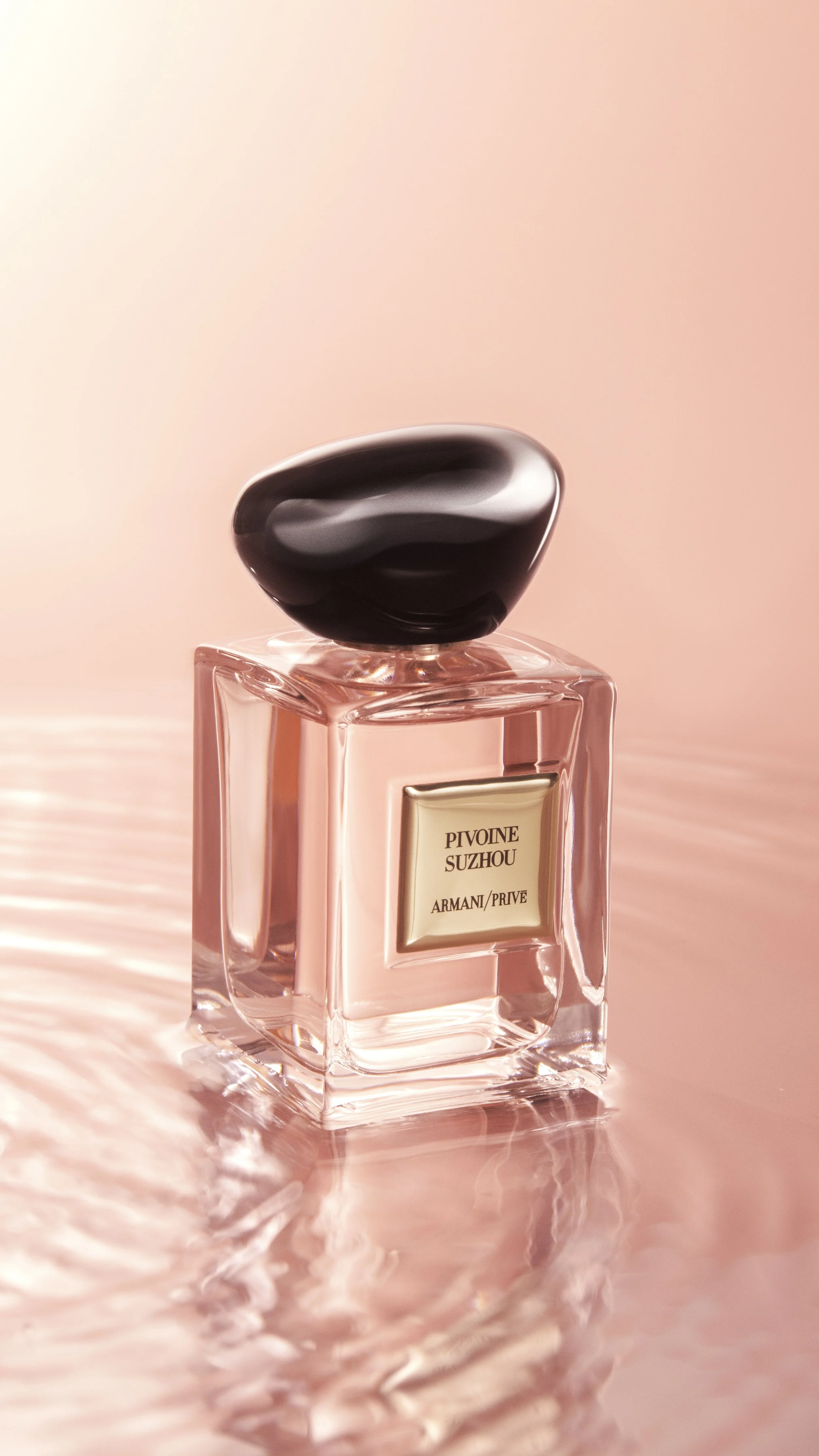 A bottle of Armani Privé perfume named Pivoine Suzhou, with a black oval cap, placed on water ripple texture