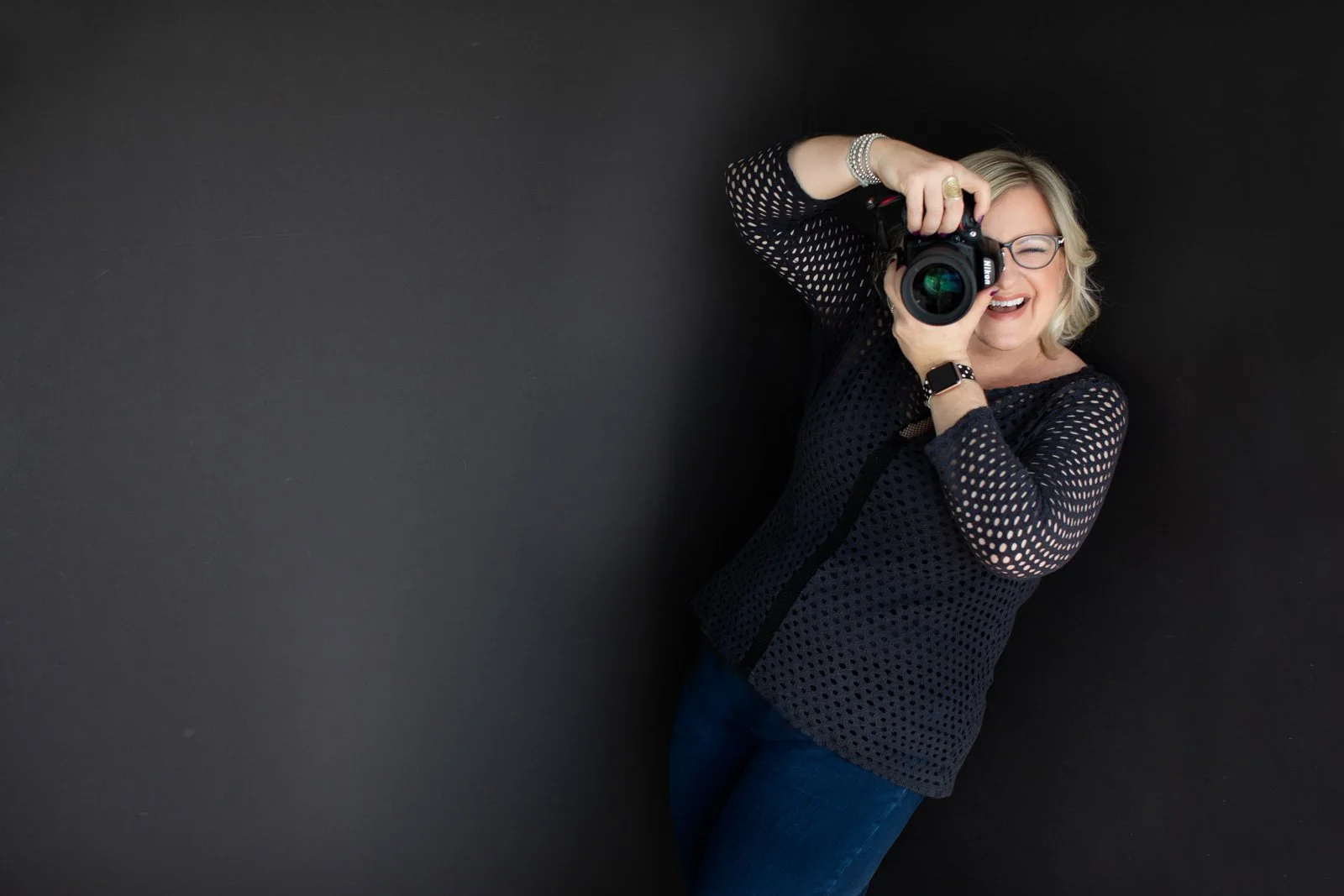 Photographer Stephanie Simpson against black background with camera to her eye