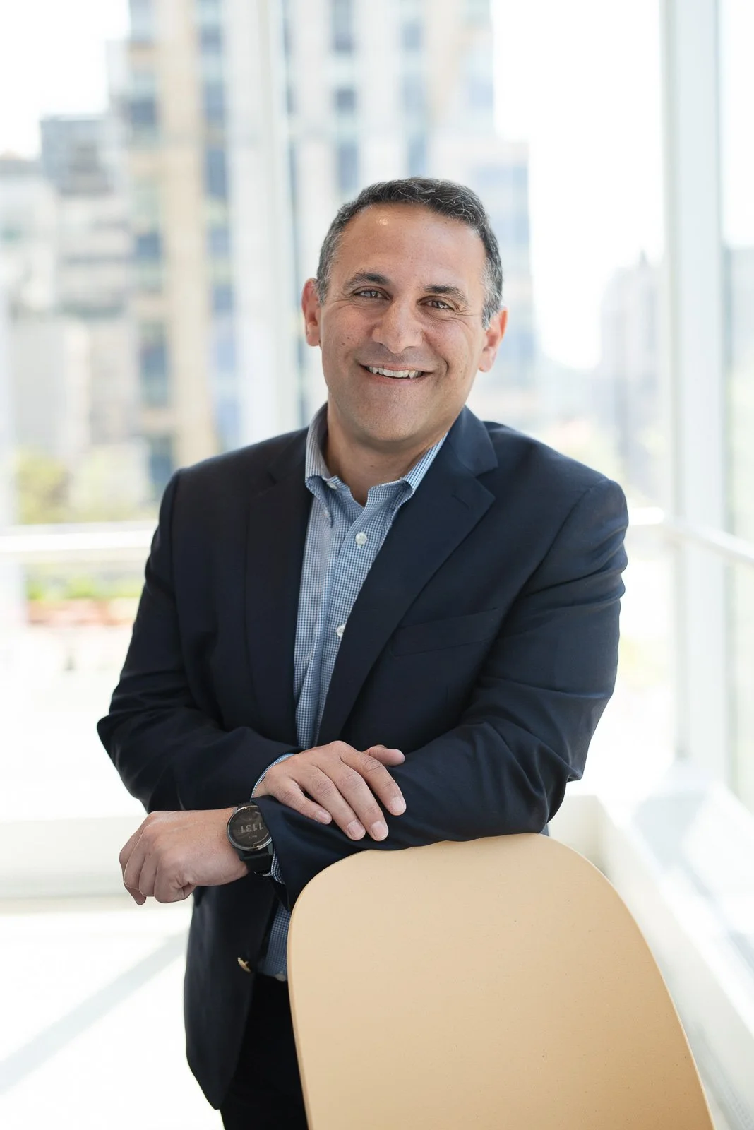 business executive with large window and city view behind him.