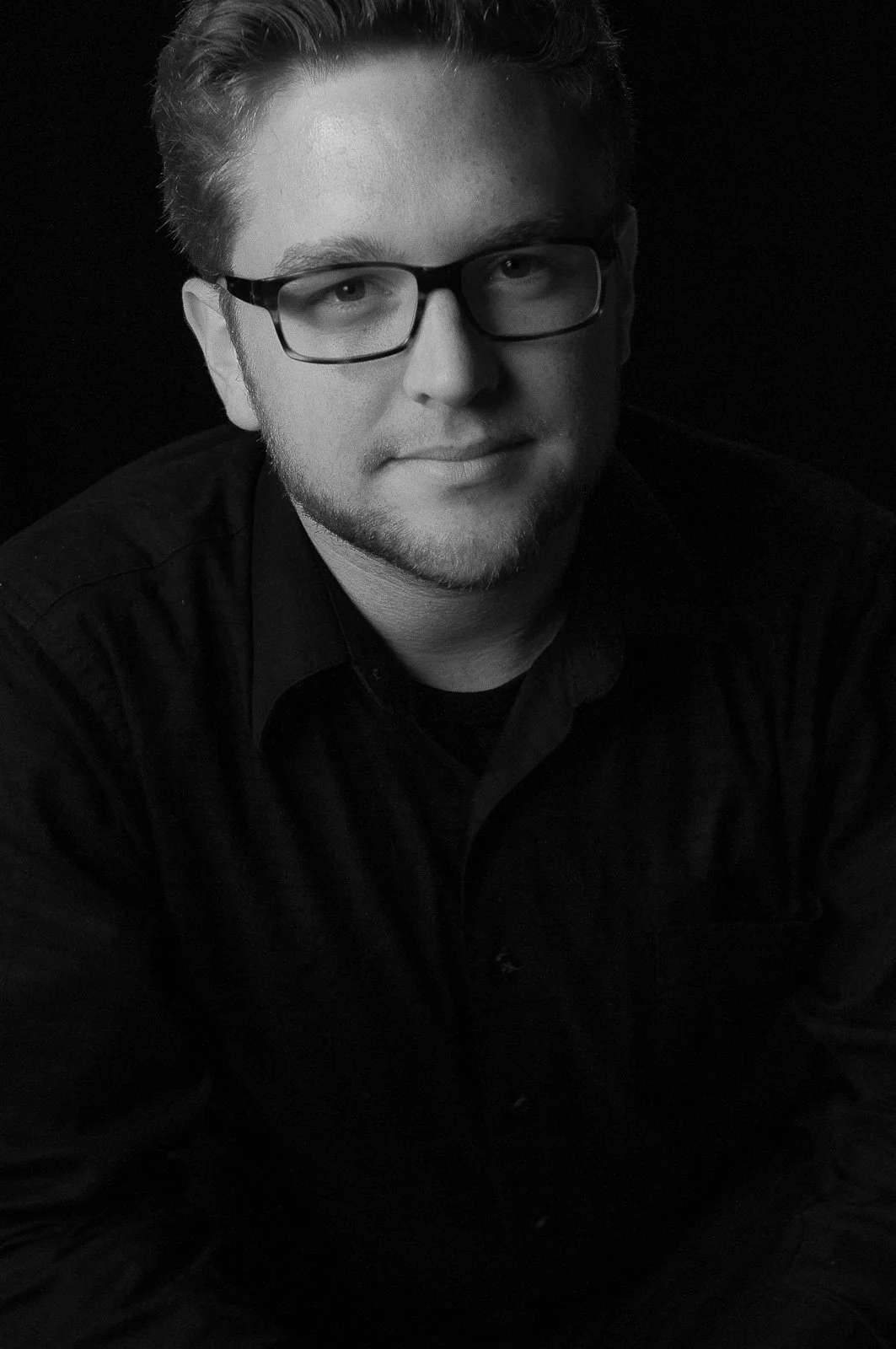 Black and white portrait of man in glasses with dramatic light