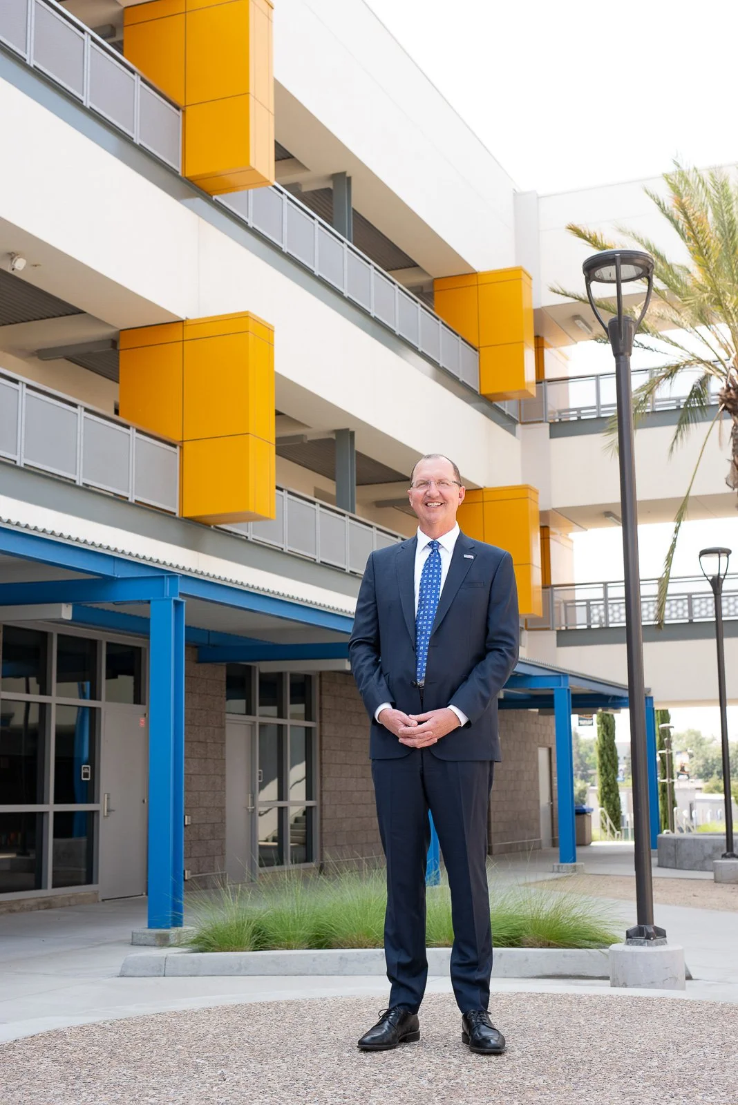 College president photographed outdoors at modern office building for leadership branding imagery.