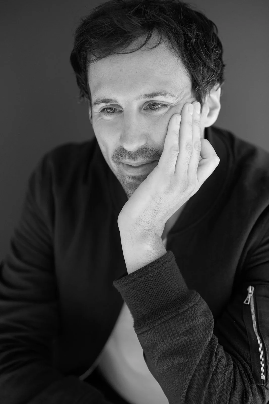 Contemplative man with hand on face in black & white