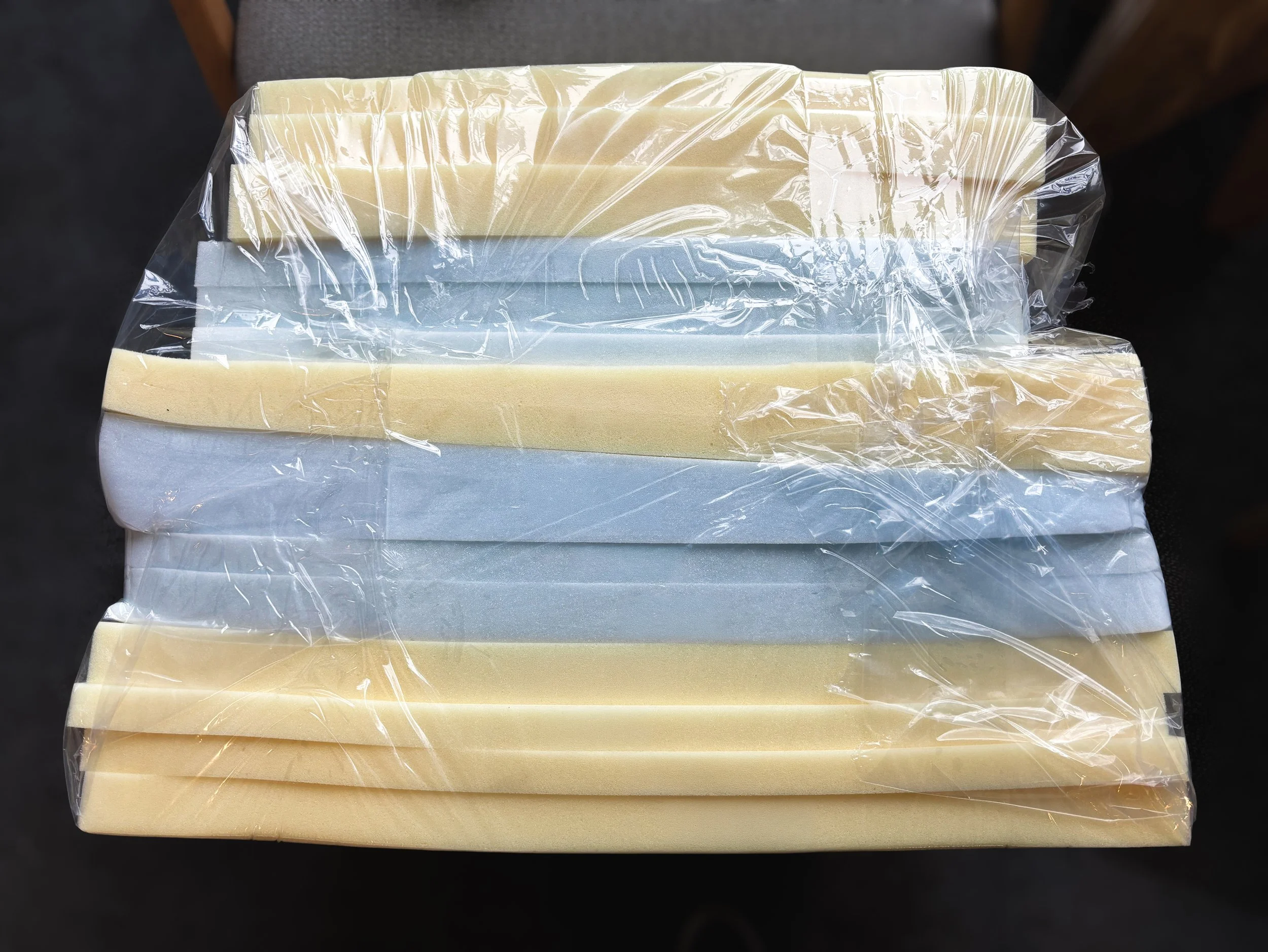 A stack of white and pale yellow rectangular soap bars wrapped in clear plastic.