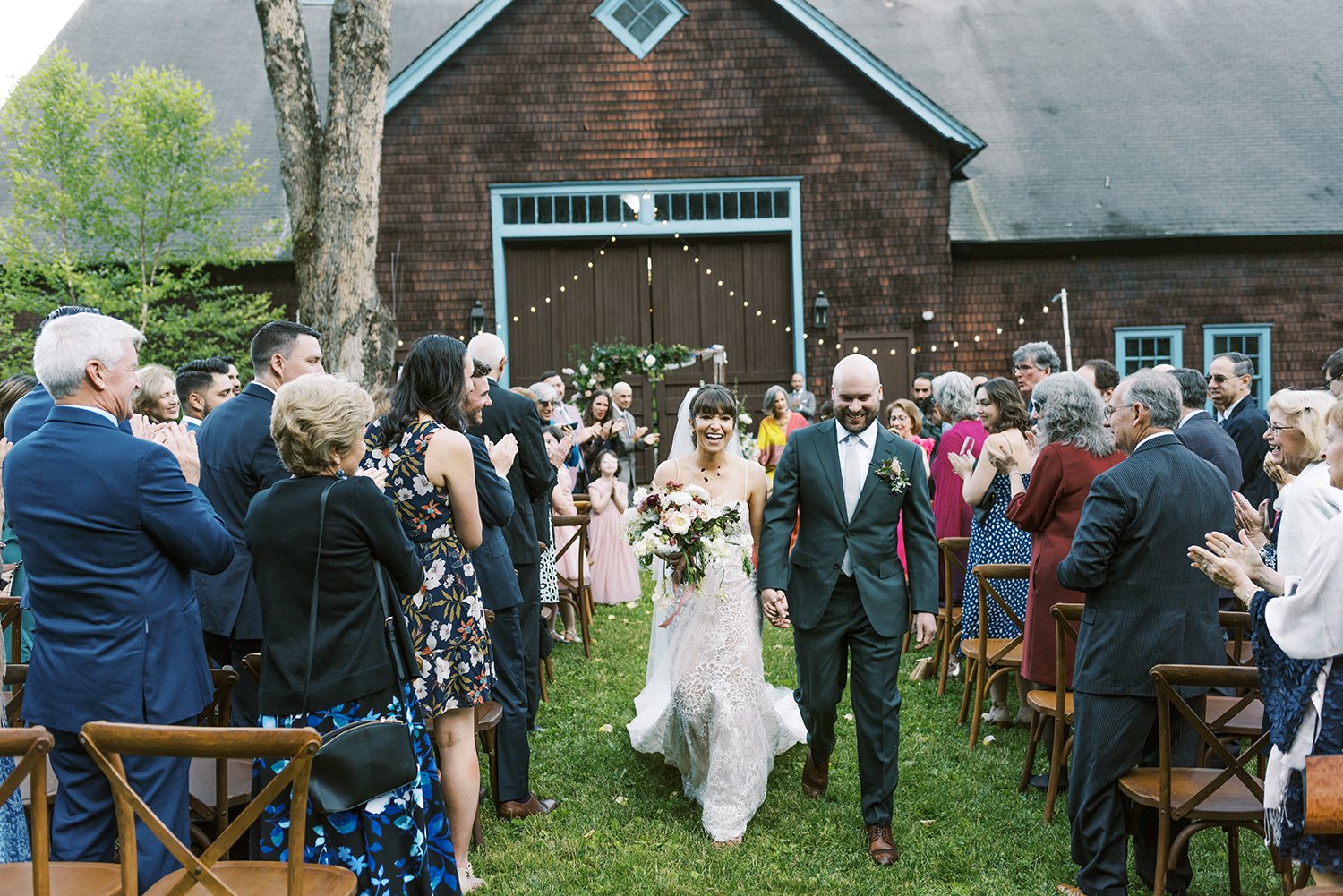 bride-and-groom-walking-behind-barn-with-people.jpg