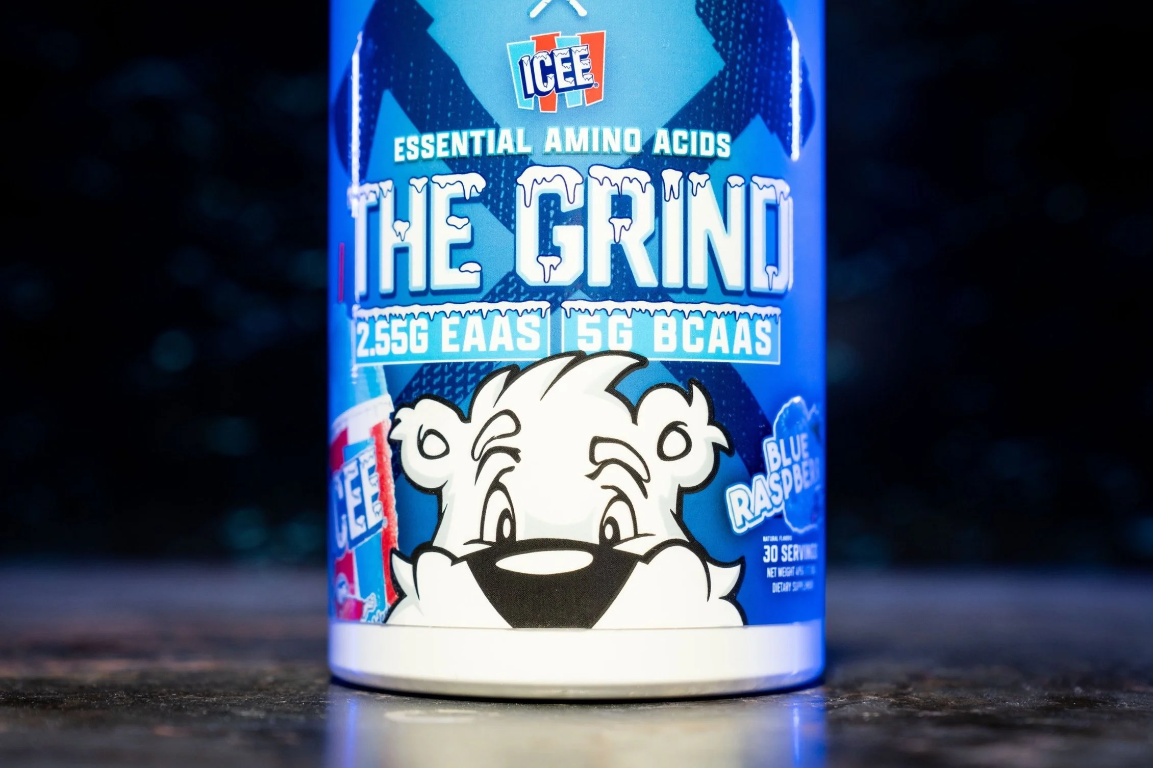 A container of ICEE The Grind Blue Raspberry flavored dietary supplement with essential amino acids, BCAAs, and EAAS, featuring a cartoon lion mascot on a dark background.