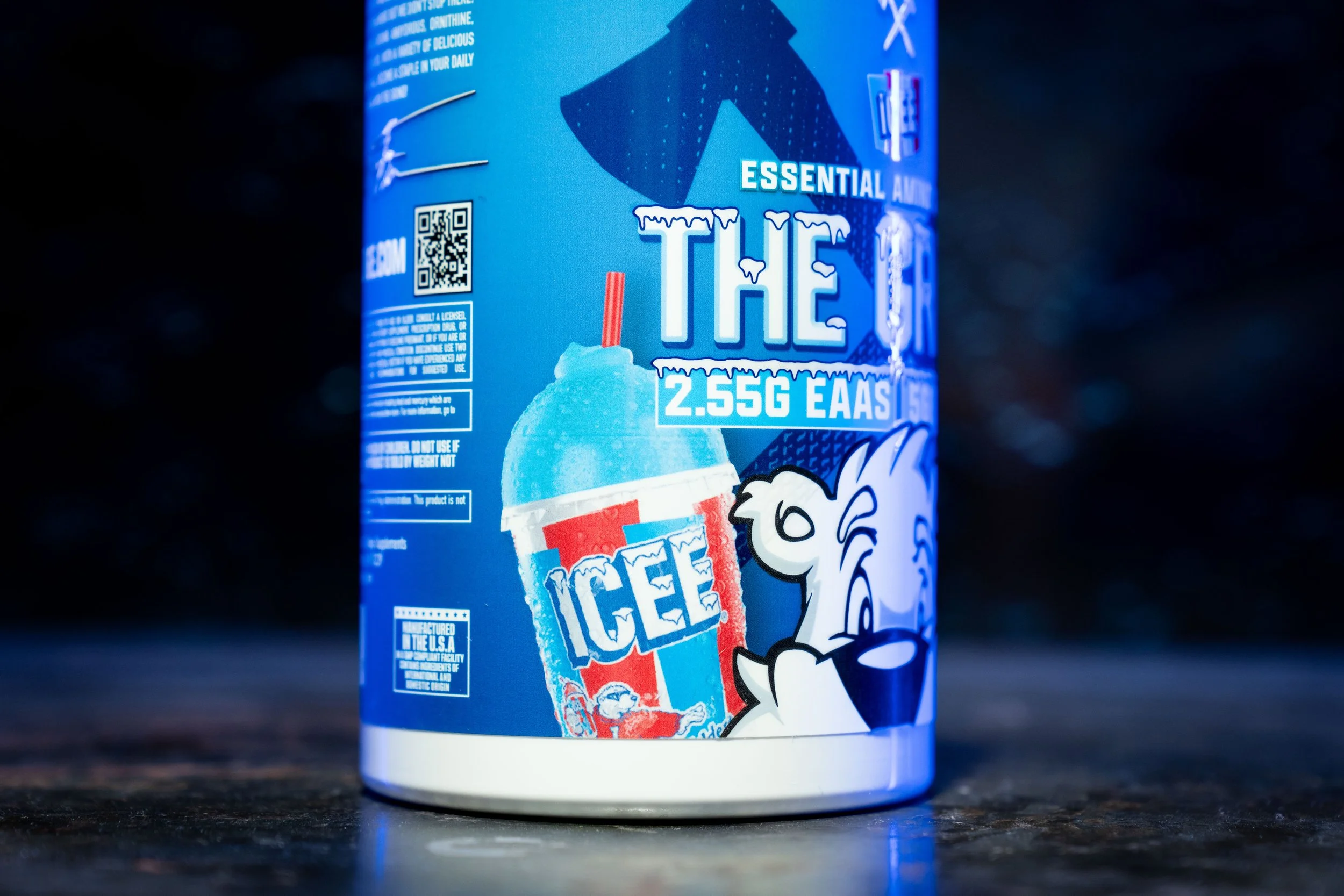 A can of ice-flavored energy drink with a cartoon animal mascot on a dark surface, featuring blue and white colors and text highlighting ingredients and certifications.