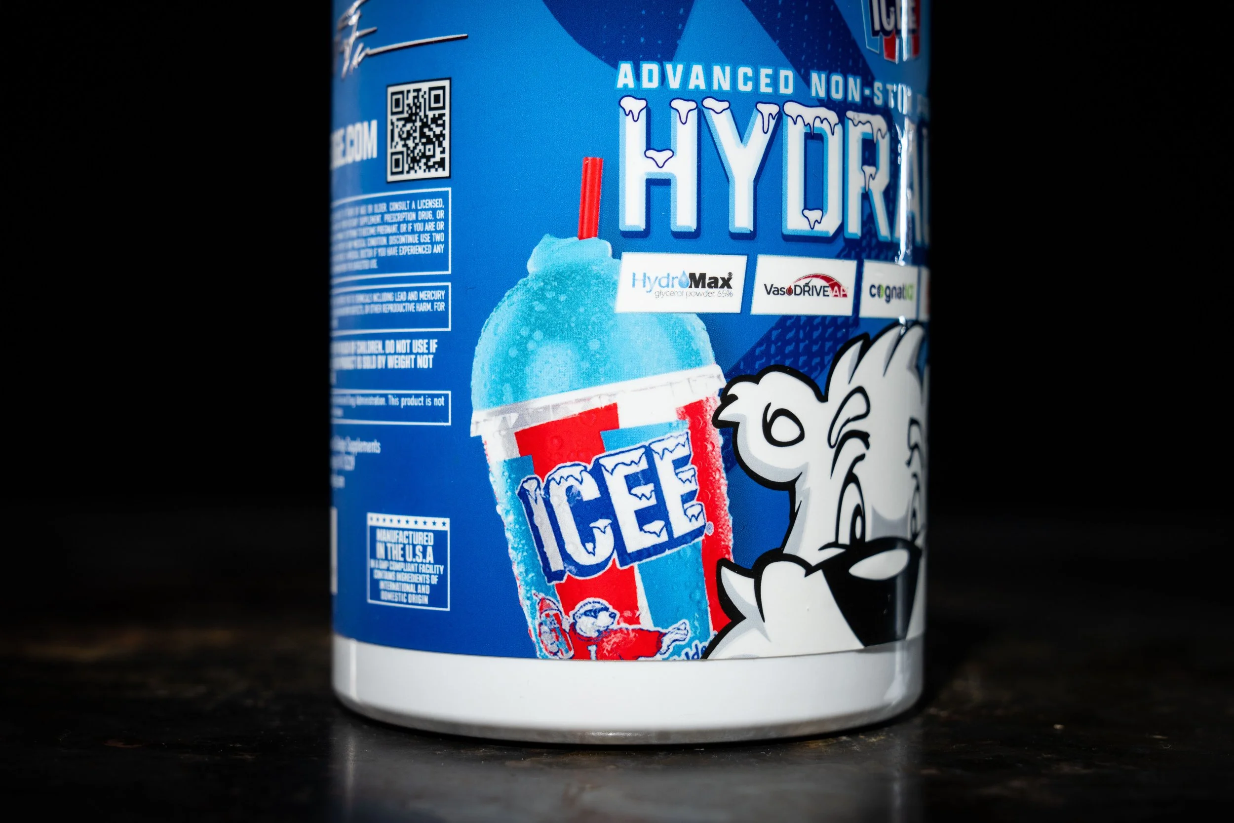 Close-up of a blue container of ice-flavored powder with a cartoon dog character on the label, featuring a picture of a blue ice drink with a red and white striped straw.