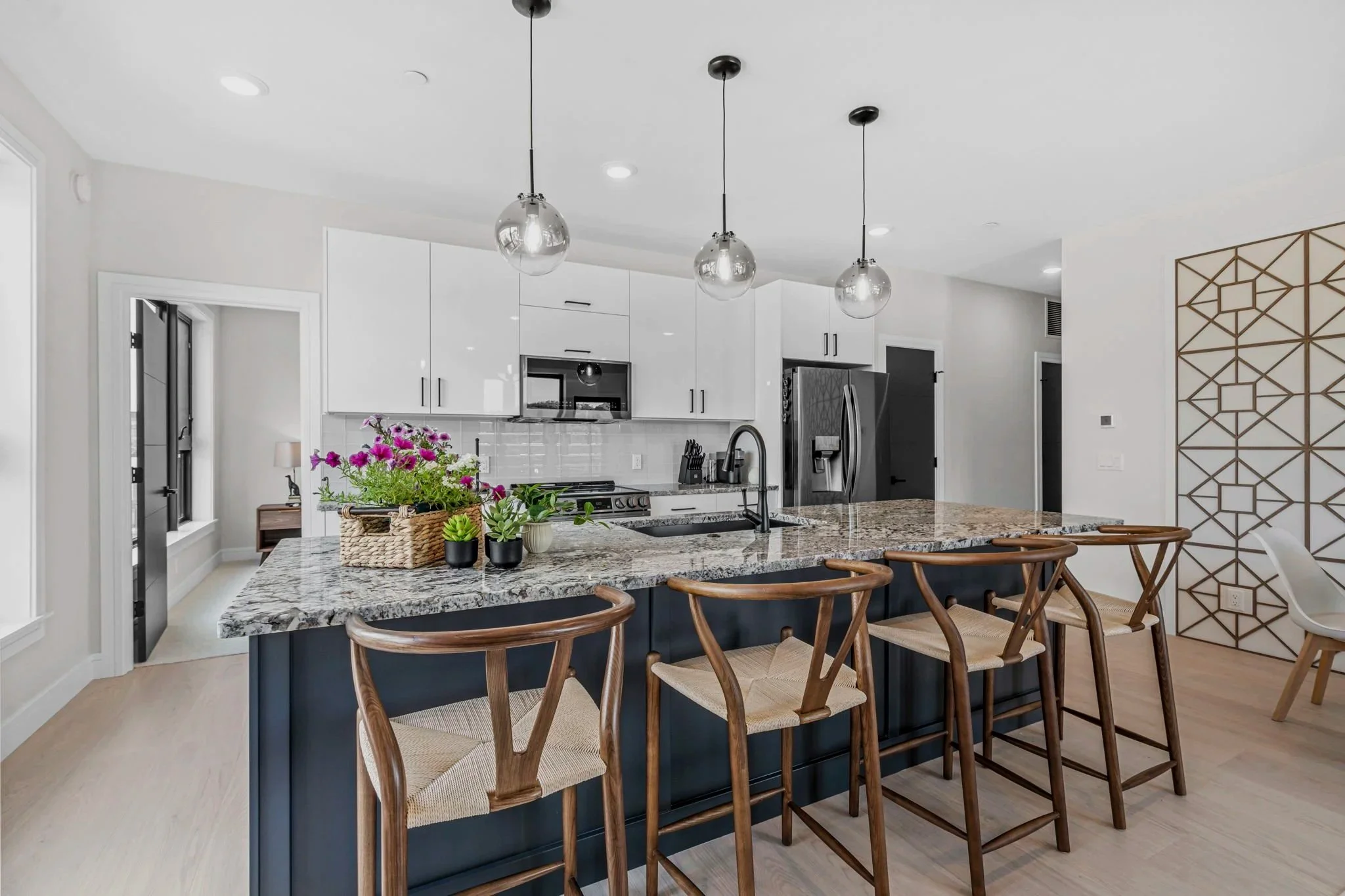 Kitchen island with four wishbone bar stools and glass pendants at Haven at the Lofts
