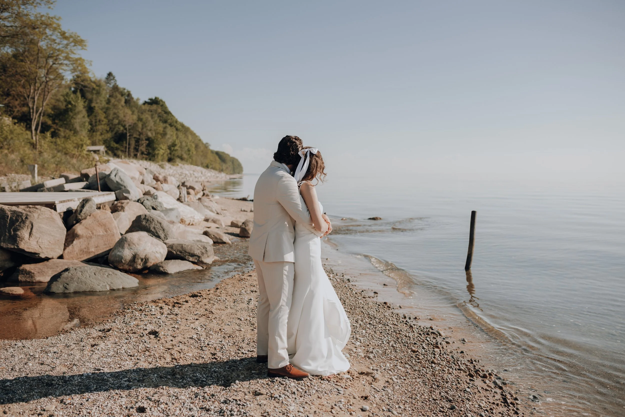 Couple embracing on the Lake Michigan shoreline at a Lighthouse Bluff wedding