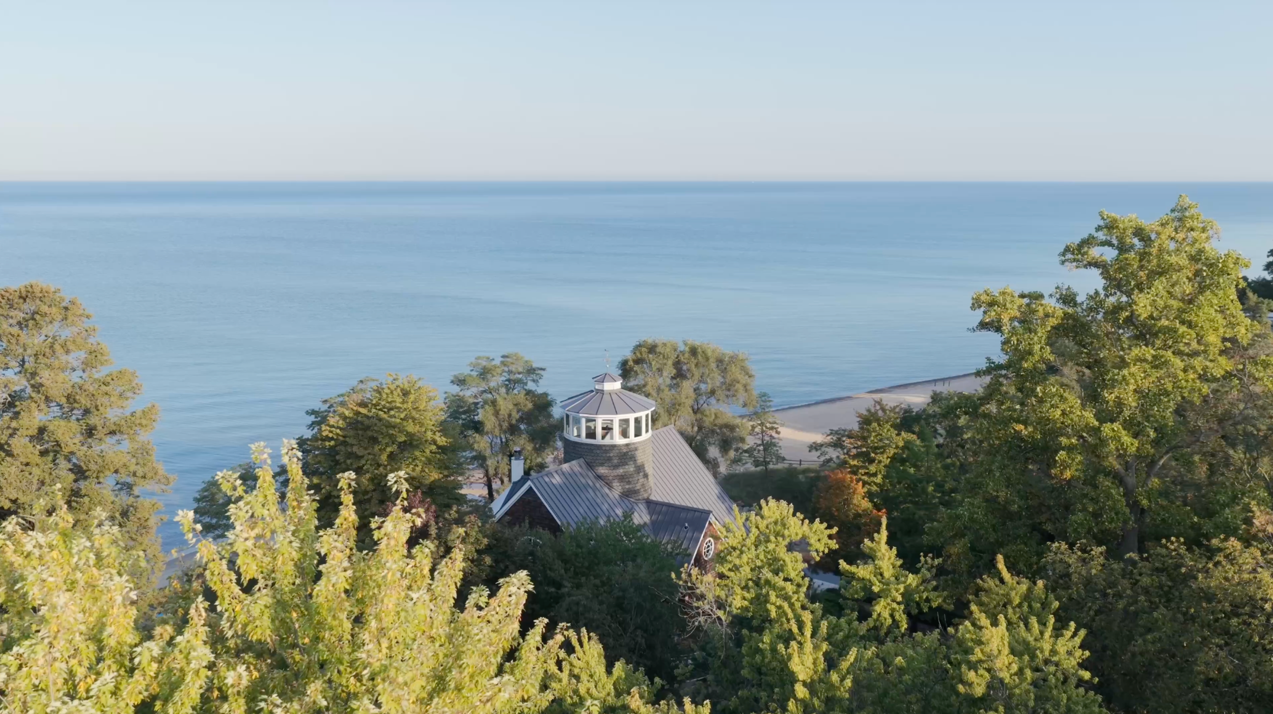 Lighthouse Bluff's crow's nest among the trees above blue Lake Michigan