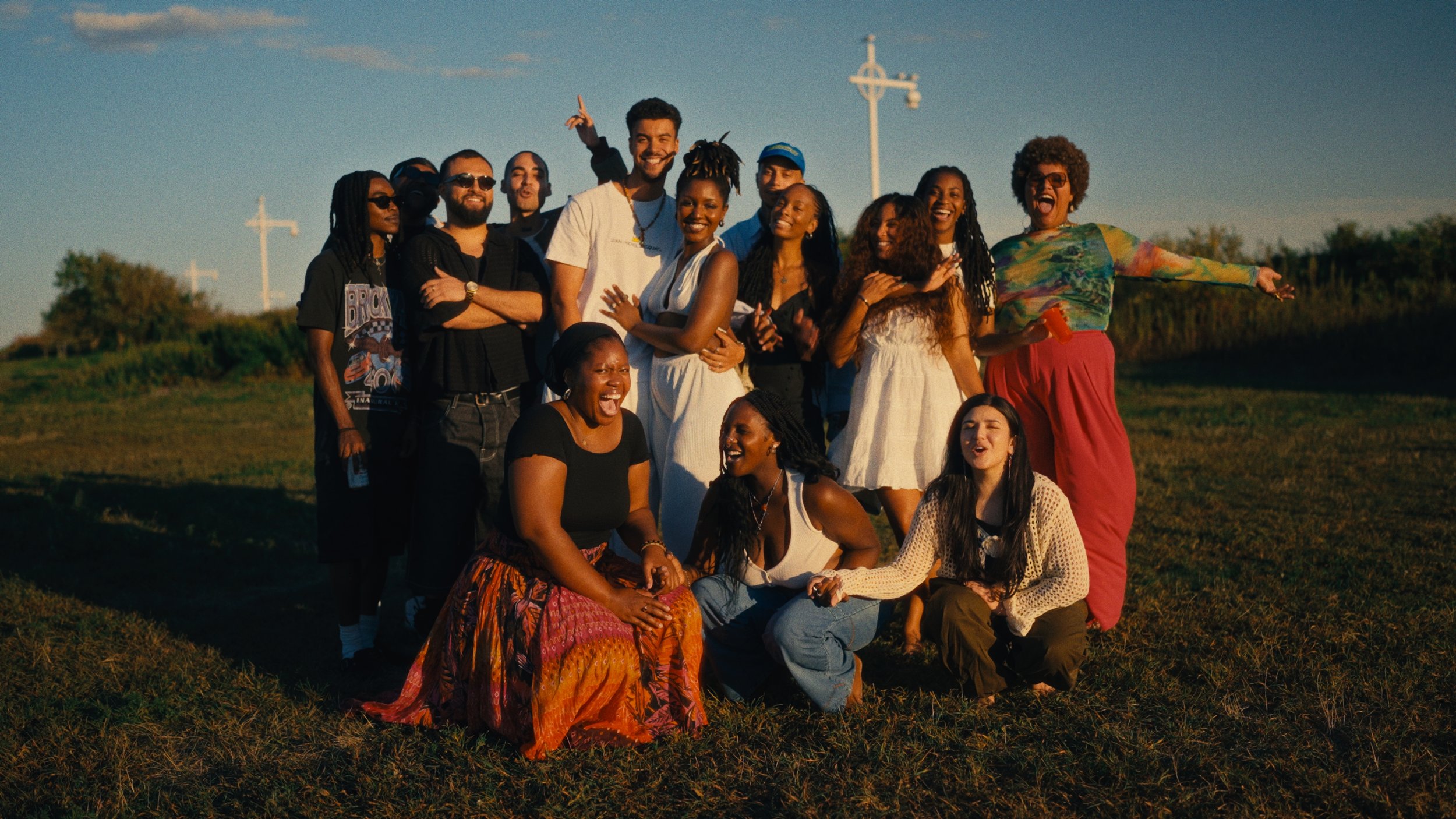 A group of diverse people smiling and enjoying an outdoor gathering during sunset.