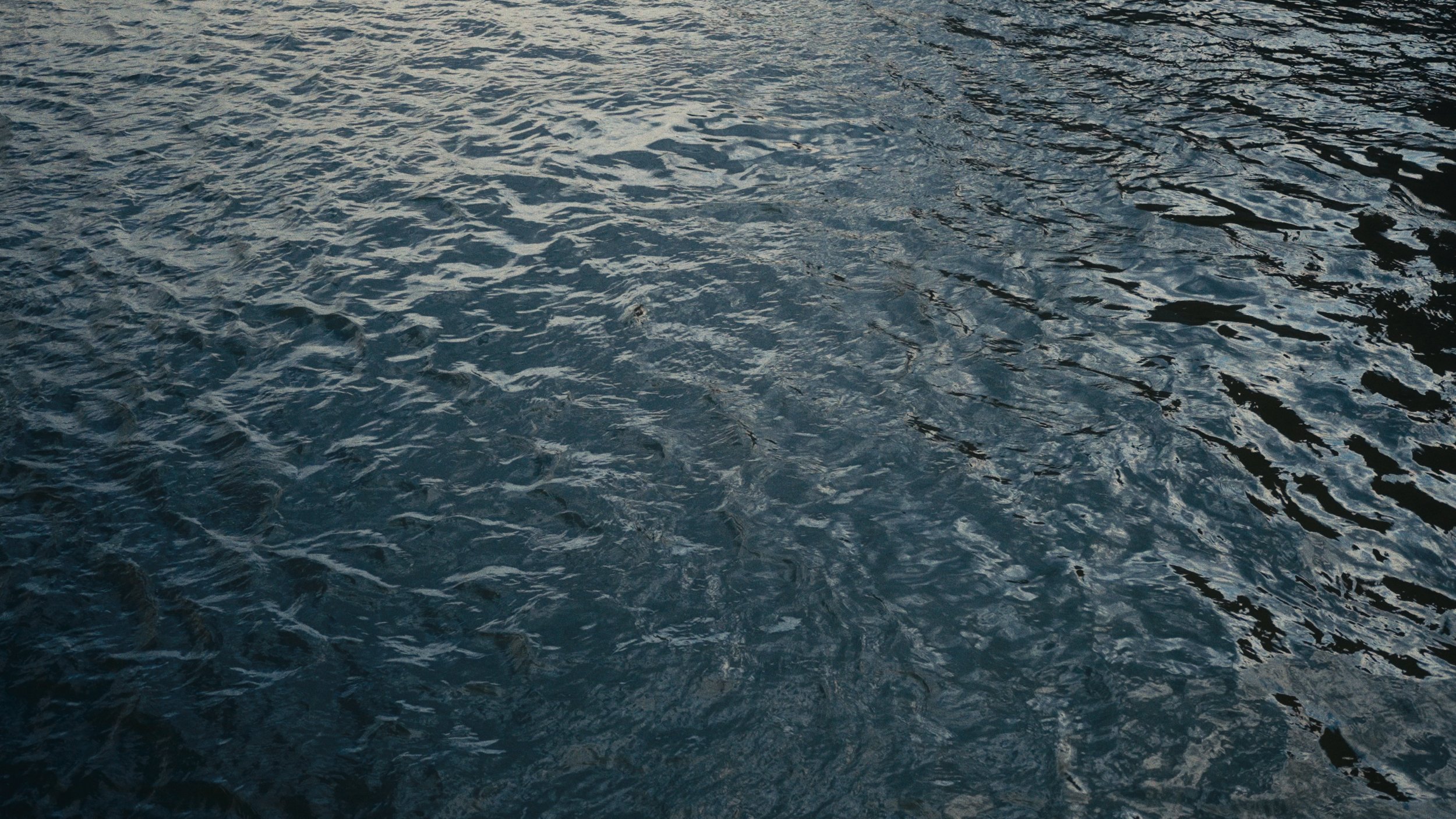 Close-up of rippling water surface with reflections, possibly in a lake or ocean.