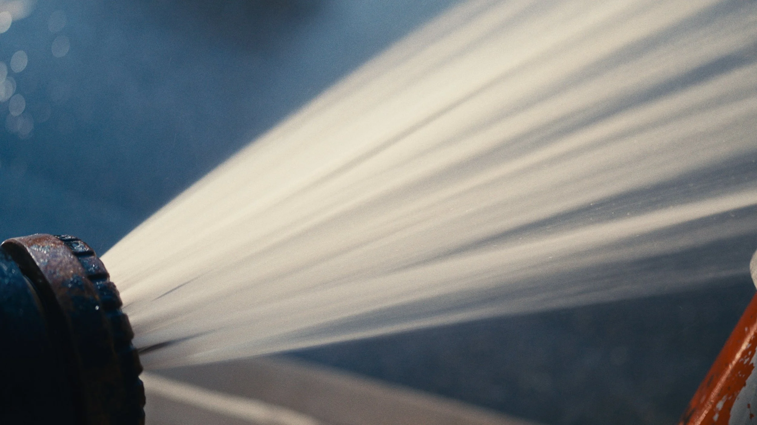 Close-up of a sprinkler nozzle spraying water against a blue background.