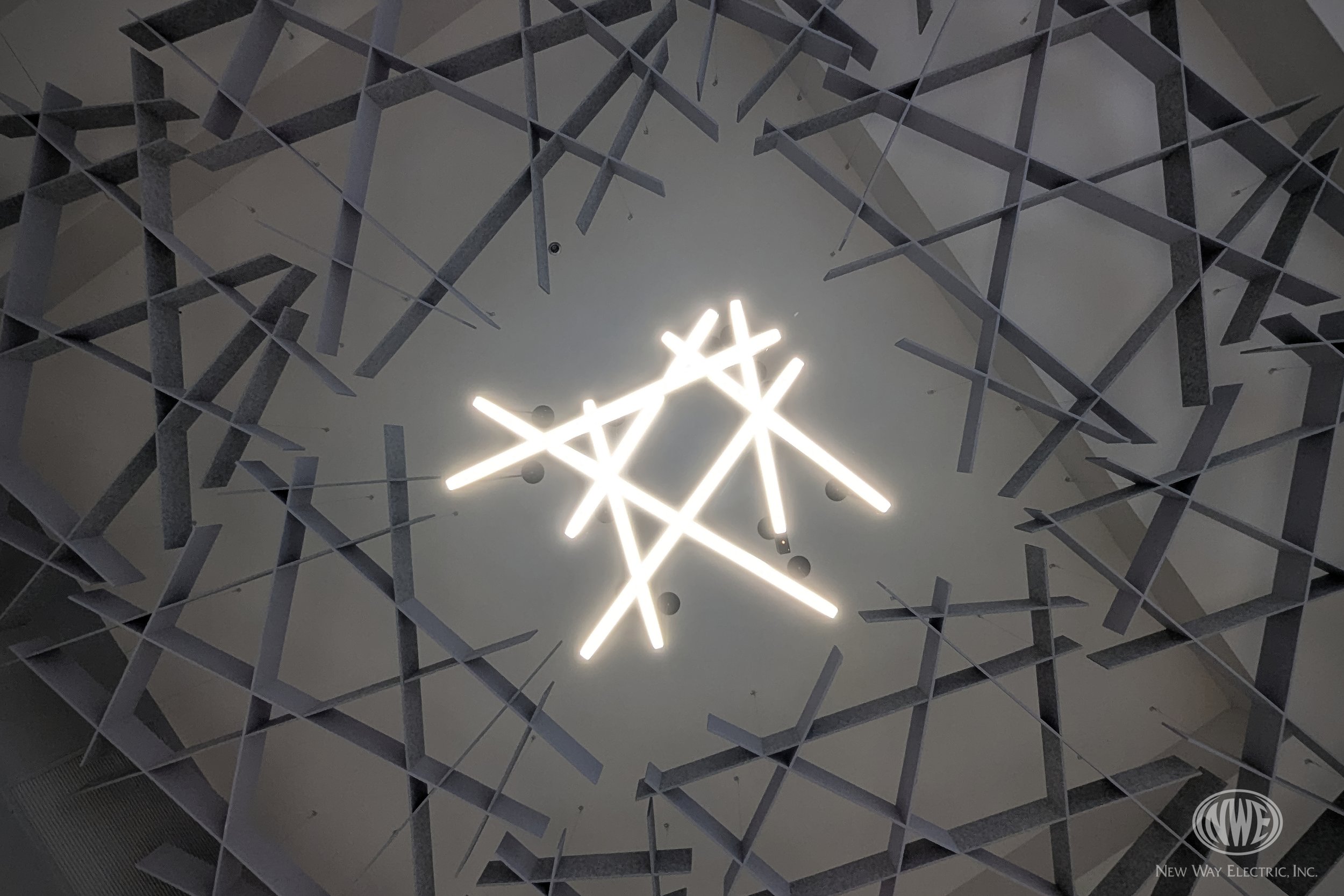 Modern ceiling design featuring geometric metallic framework with a bright star-shaped light fixture at the center.