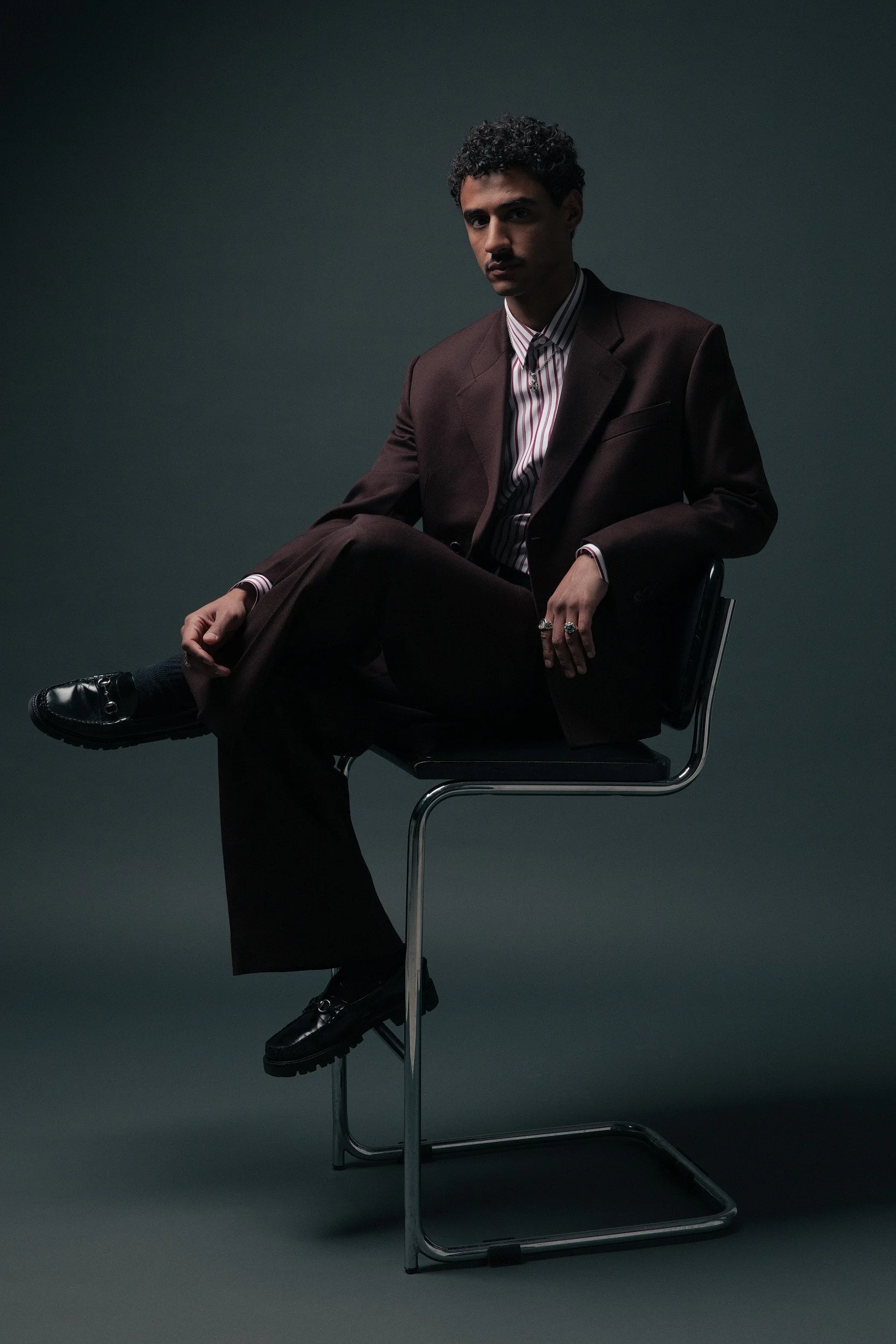 man in a double breasted deep burgundy custom suit with wide leg pants and a striped shirt and black loafers