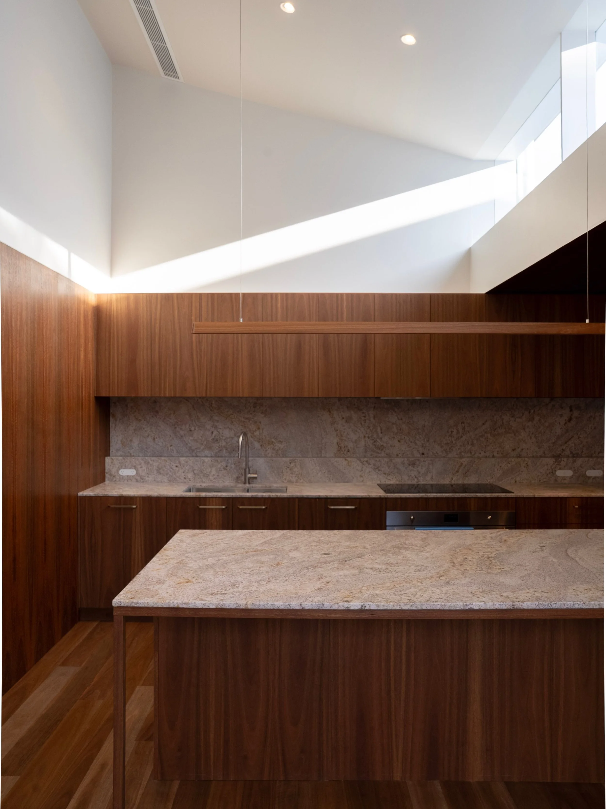 Adamstown Heights, a kitchen shaped by warmth, light and material. 
Rich timber joinery and natural stone bring depth to the space, while the high ceilings and clerestory windows draw natural light in from above. 
A considered palette, beautifully ex