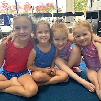A group of young children sitting in a classroom, holding books, participating in a reading activity.