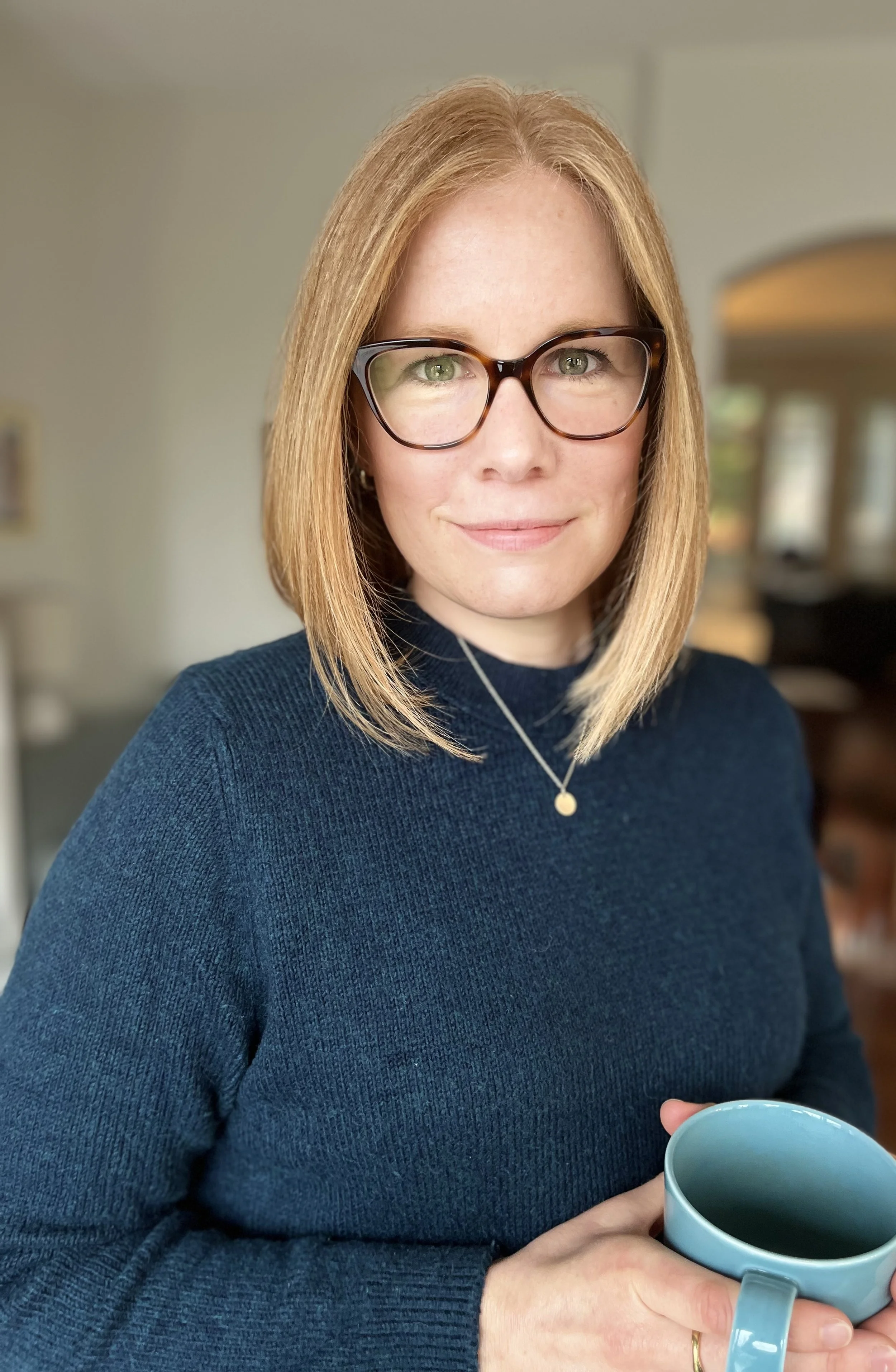 Robyn Kozak, trauma therapist in Burnaby BC, wearing glasses and sweater holding a mug