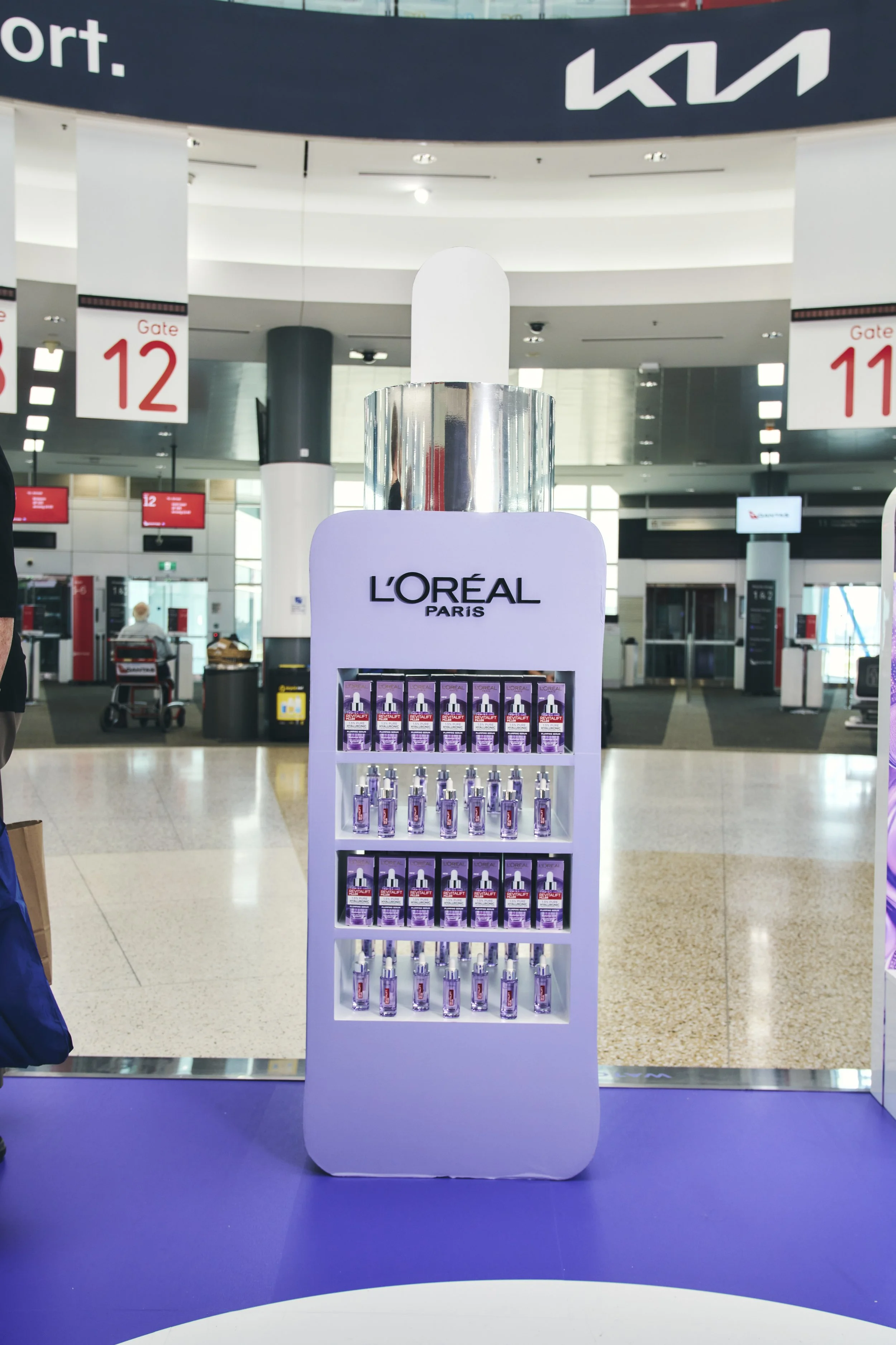 Display stand with L'Oreal Paris skincare products at an airport.