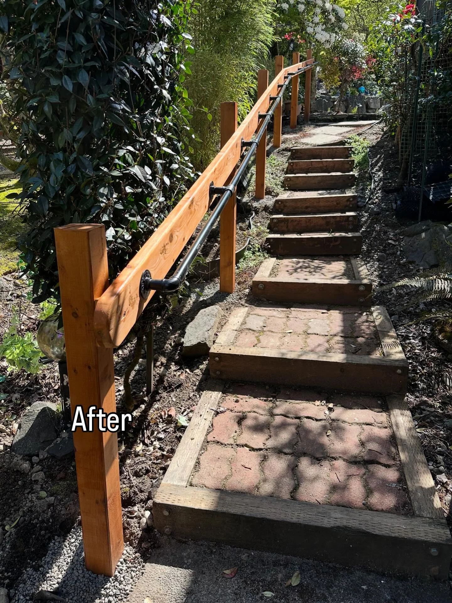 Built a handrail along this garden stairway for a client &mdash; cedar posts with black pipe rail hardware. The path winds through a beautiful established landscape and gets a lot of use, so having something solid to hold onto made a real difference.