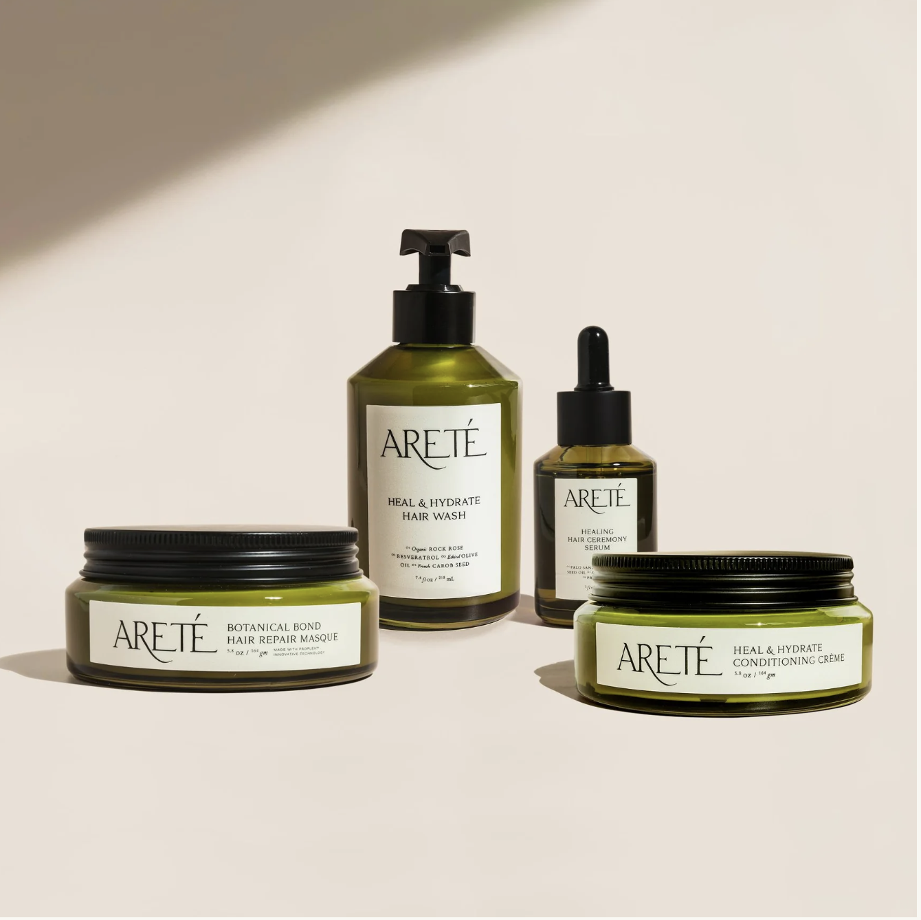 Collection of ARETÉ hair care products including shampoo, conditioner, hair masque, and serum on a white background.