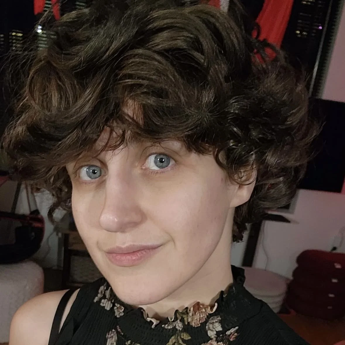 person with short wavy hair smirking