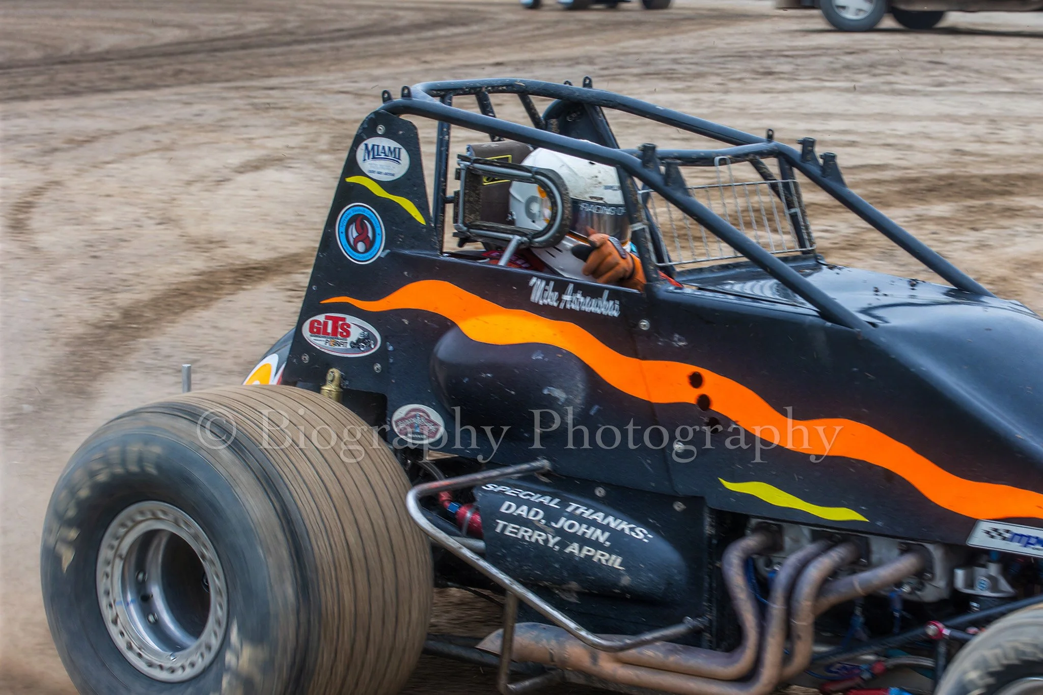 Sprint car driver pointing at the camera as they drive by at Silver Bullet Speedway