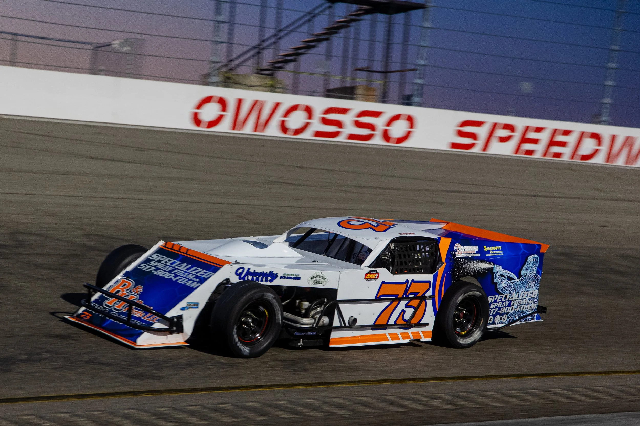 an image taken by a professional motorsport photographer of a modified race car racing on an asphalt short track in Michigan