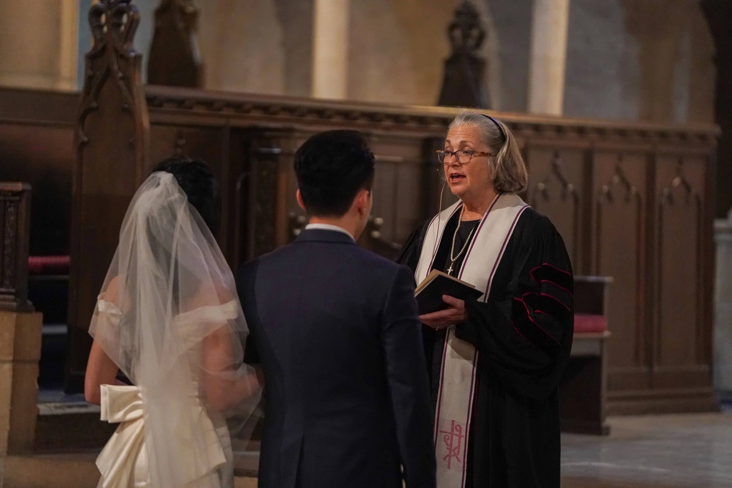 A wedding ceremony with a bride, groom, and a minister or officiant inside a church.
