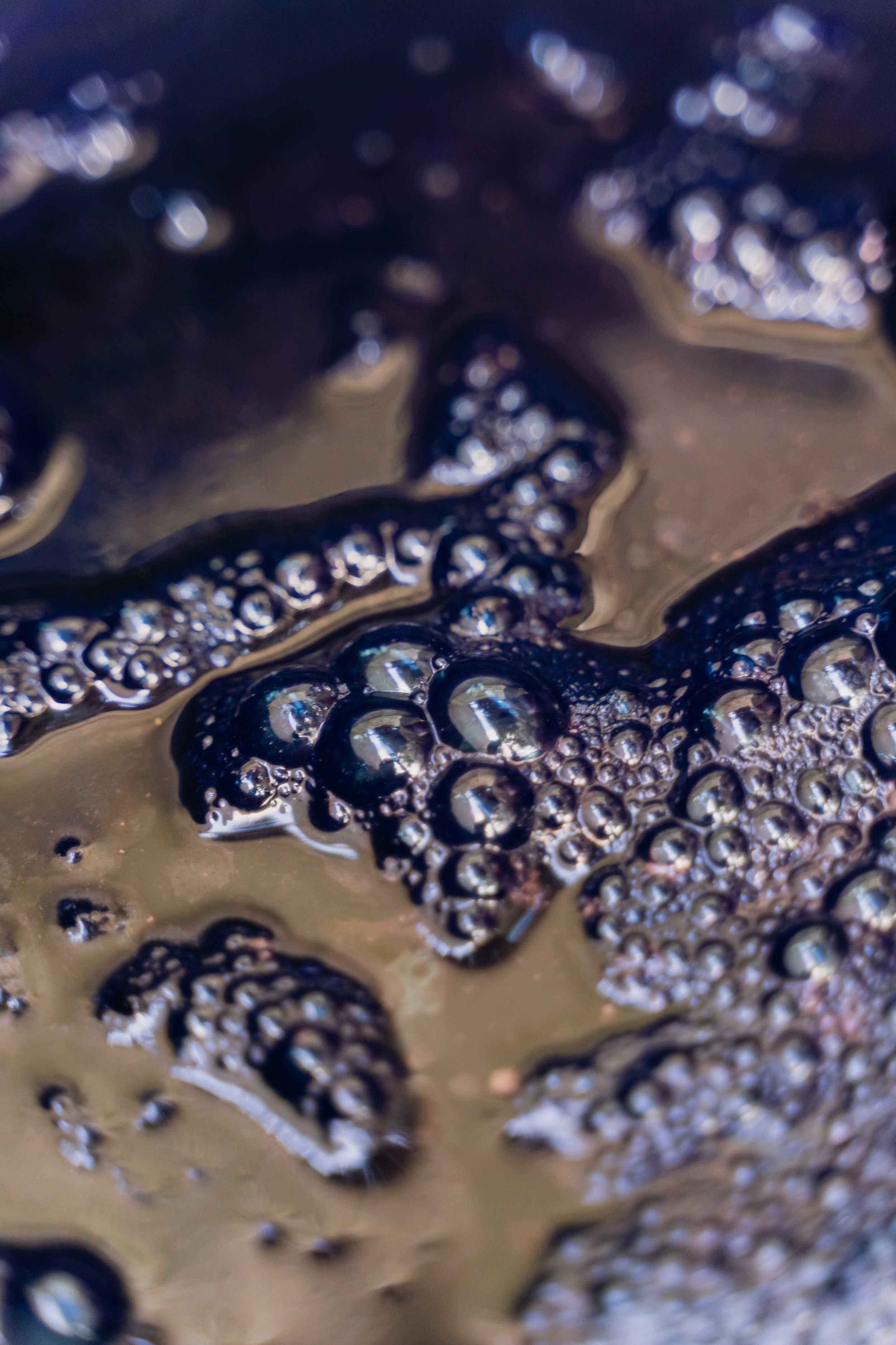 Close-up of dark bubbles on a surface, possibly foam or liquid with bubbles