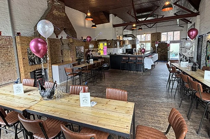 Event space decorated with balloons and tables for a celebration, featuring the upstairs bar area and exposed brick and wooden interior.