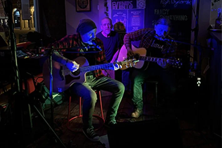 Two musicians playing acoustic guitars on stage