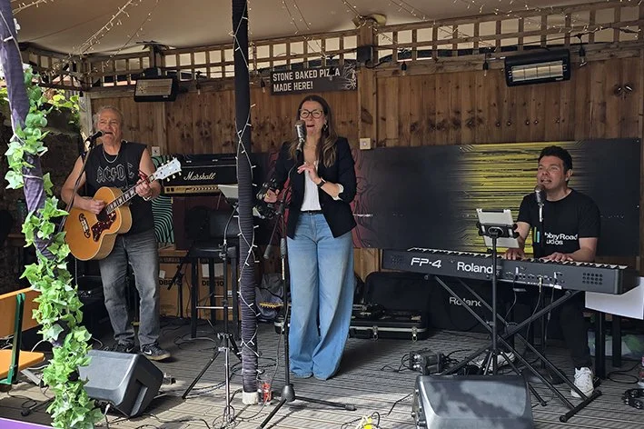 A three-person band performing on an outdoor stage.