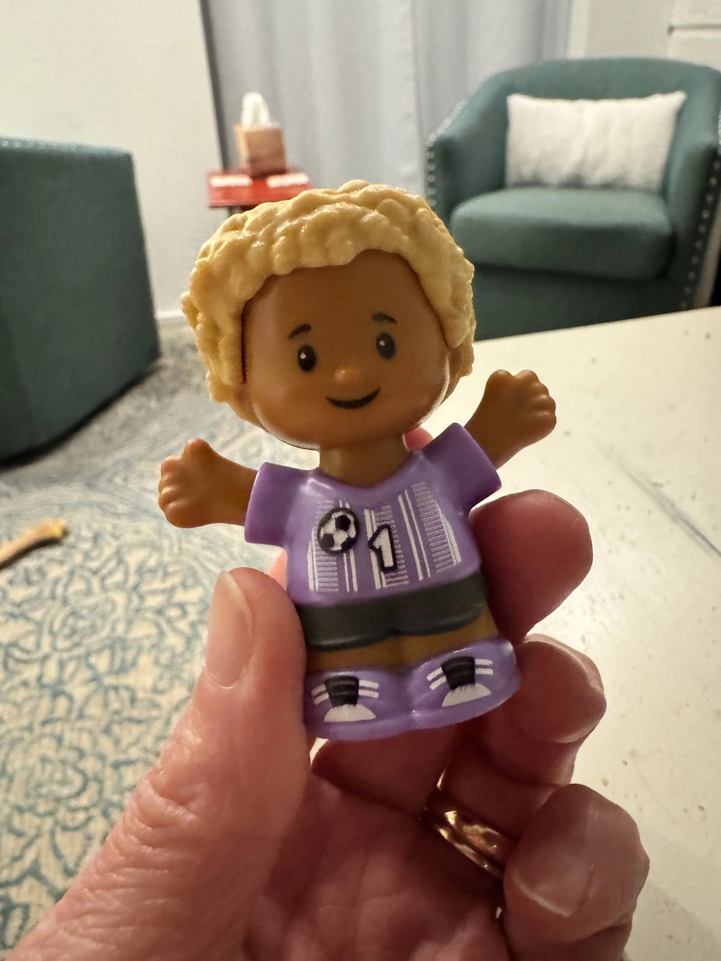 little toddler fisher price toy with curly hair and smile.