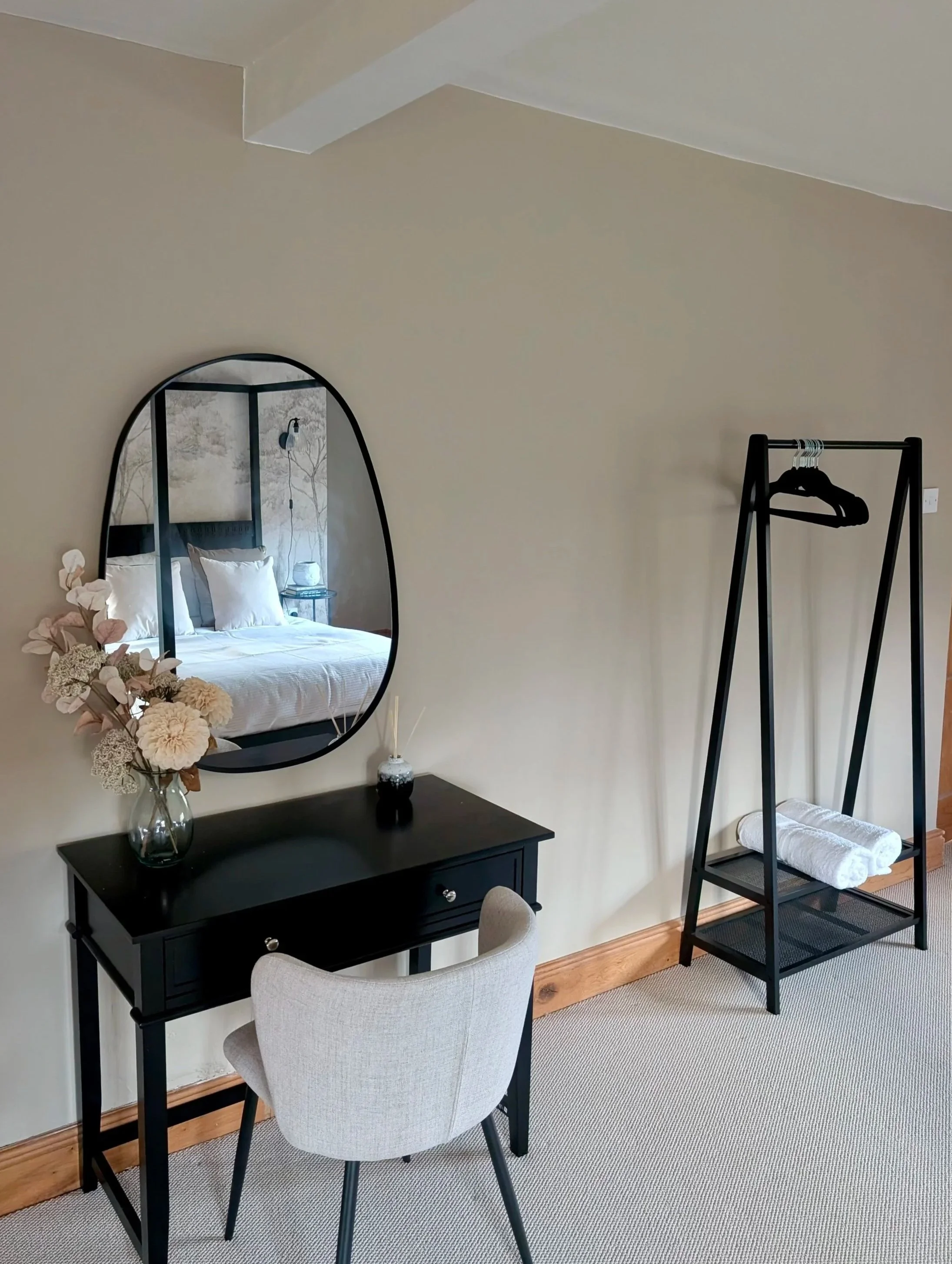 Styled bedroom corner with black console table, statement mirror and modern clothing rail in a beautifully designed UK holiday let. This thoughtfully curated interior combines practical storage with elegant, neutral décor to enhance light, space and 