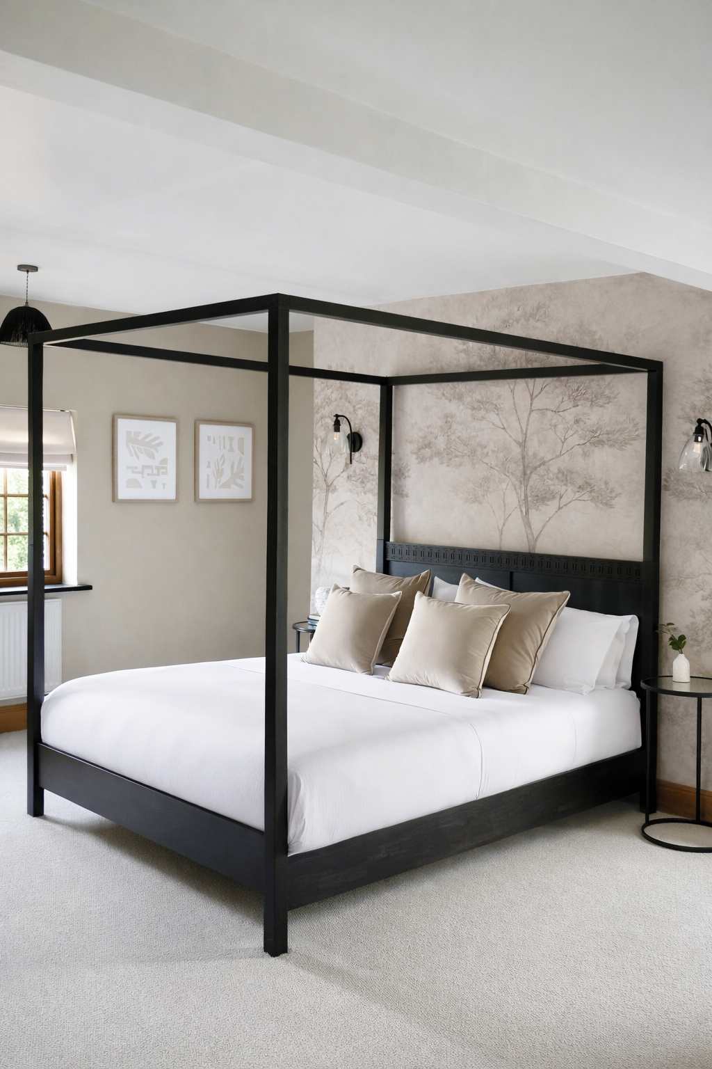 Luxury master bedroom with black four-poster bed, layered neutral bedding and feature botanical wallpaper in a Wales countryside holiday home. A boutique-style interior design scheme combining contemporary comfort with warm natural textures and soft,