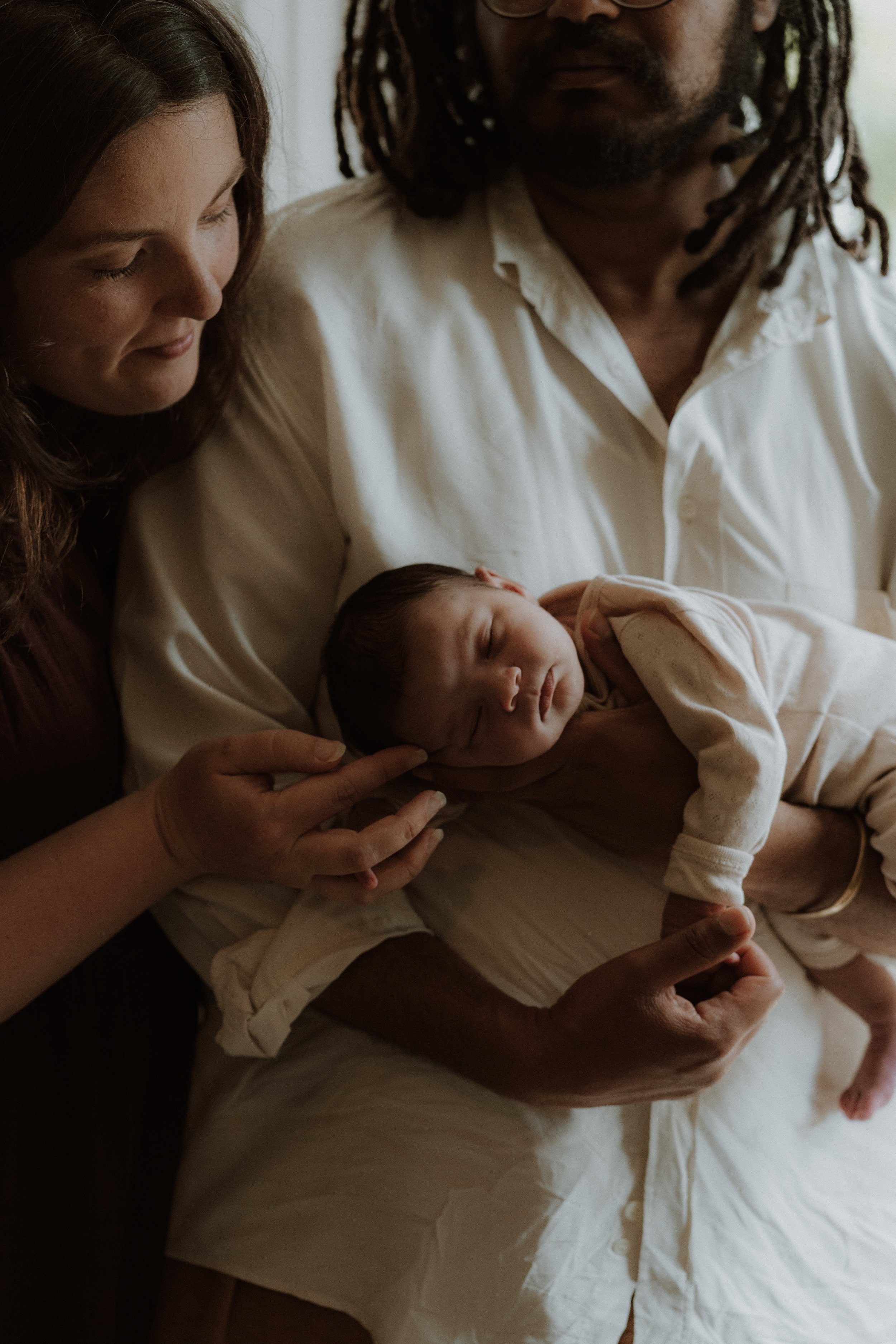New parents cuddling their newborn baby during an in-home newborn photography session in Oxford