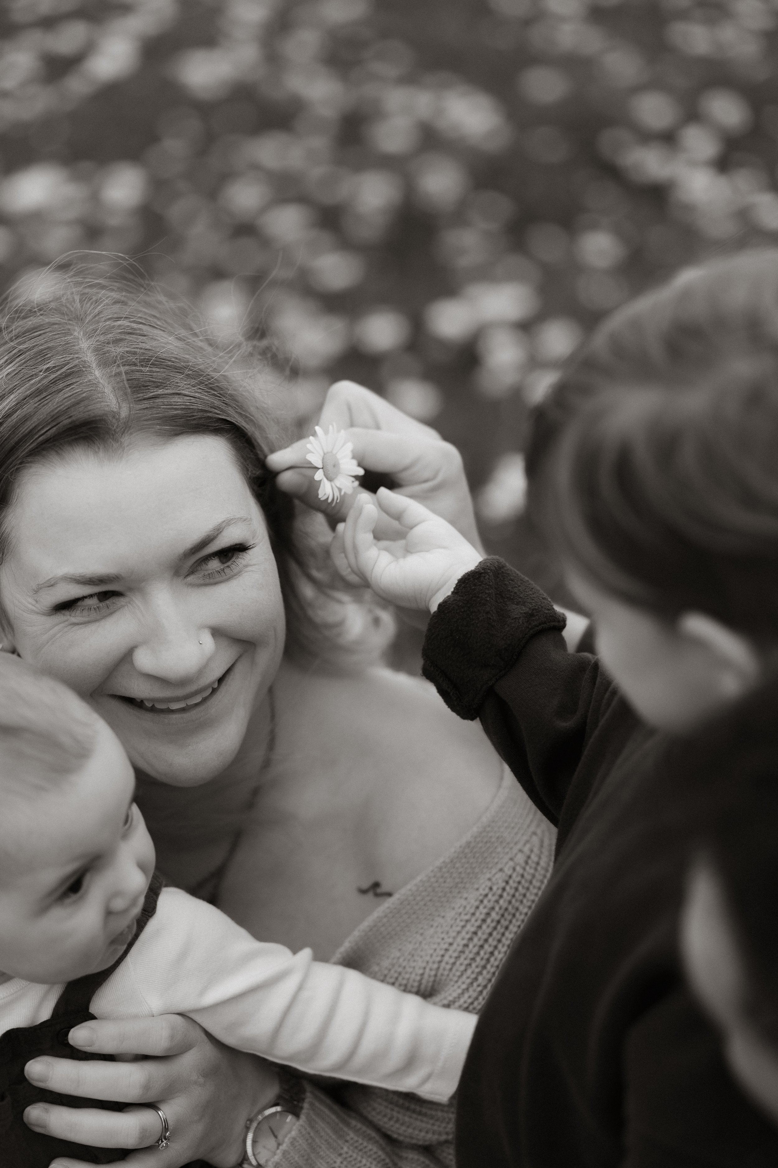 A young boy tucking a daisy behind his mum’s ear during a relaxed outdoor family photography session near Wantage, Oxfordshire.