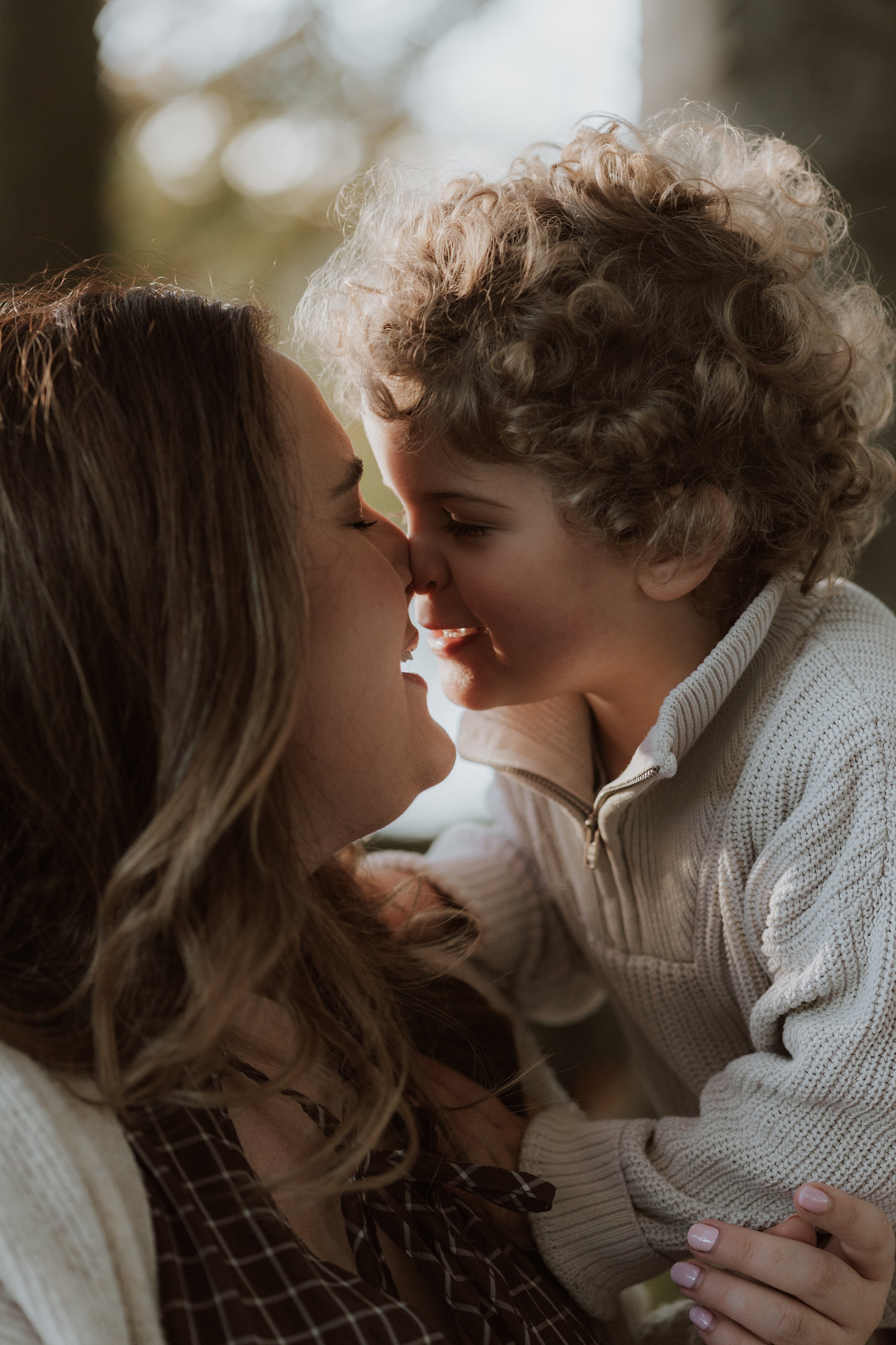 Mother and son sharing a nose kiss during an outdoor family photography session in the Cotswolds, captured by an Oxfordshire family photographer in soft golden evening light.