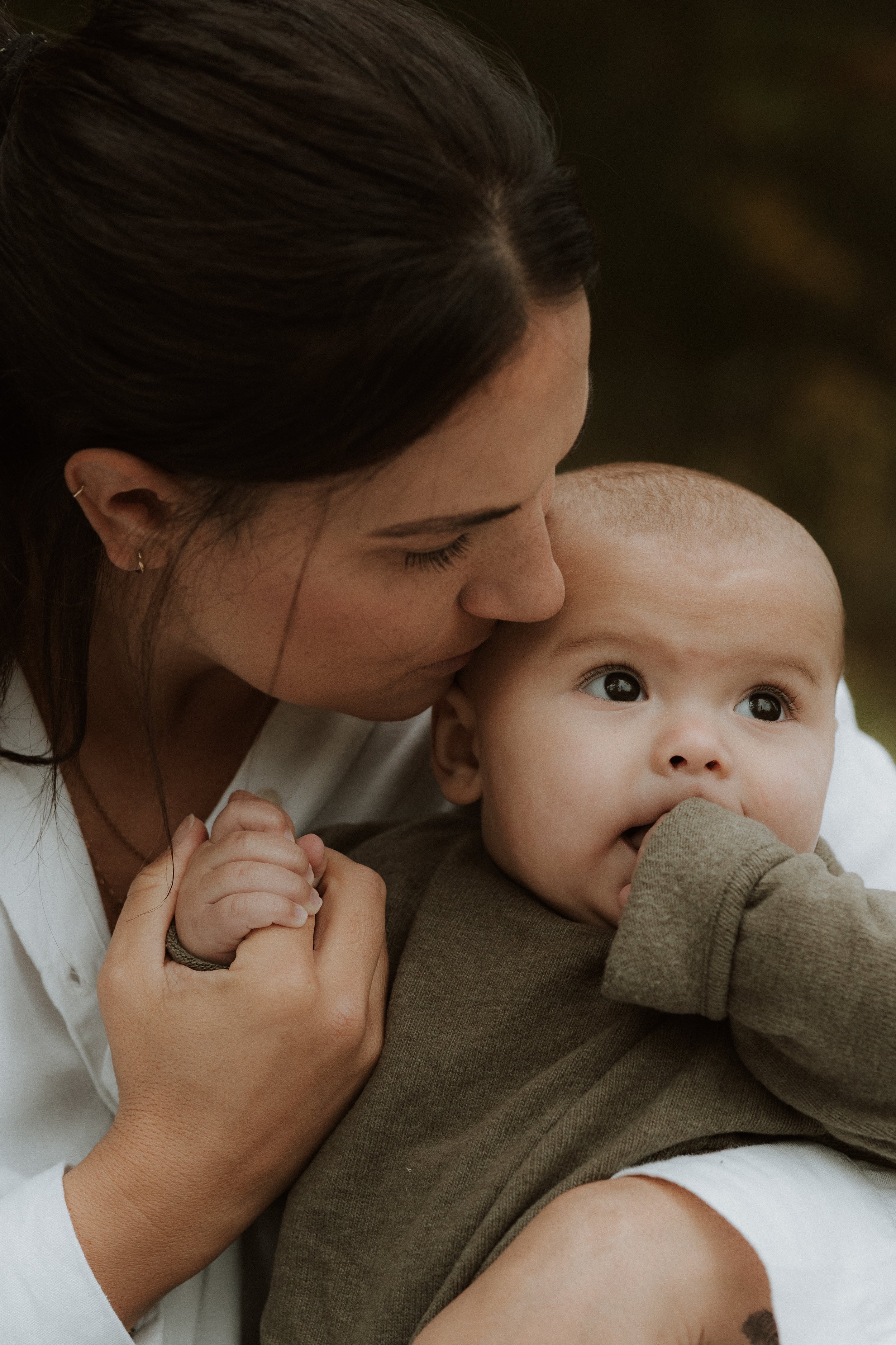 Mum kissing her baby on the head during a natural family photography session in the Cotswolds