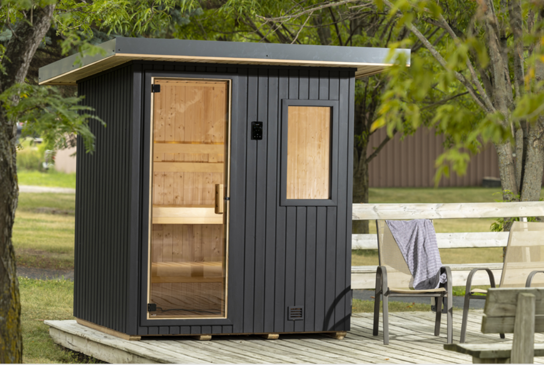 A Sauna  NorthStar black and natural wood sauna on a wooden deck outdoors, surrounded by trees and greenery.