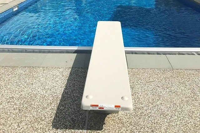 A white diving block positioned at the edge of a swimming pool.