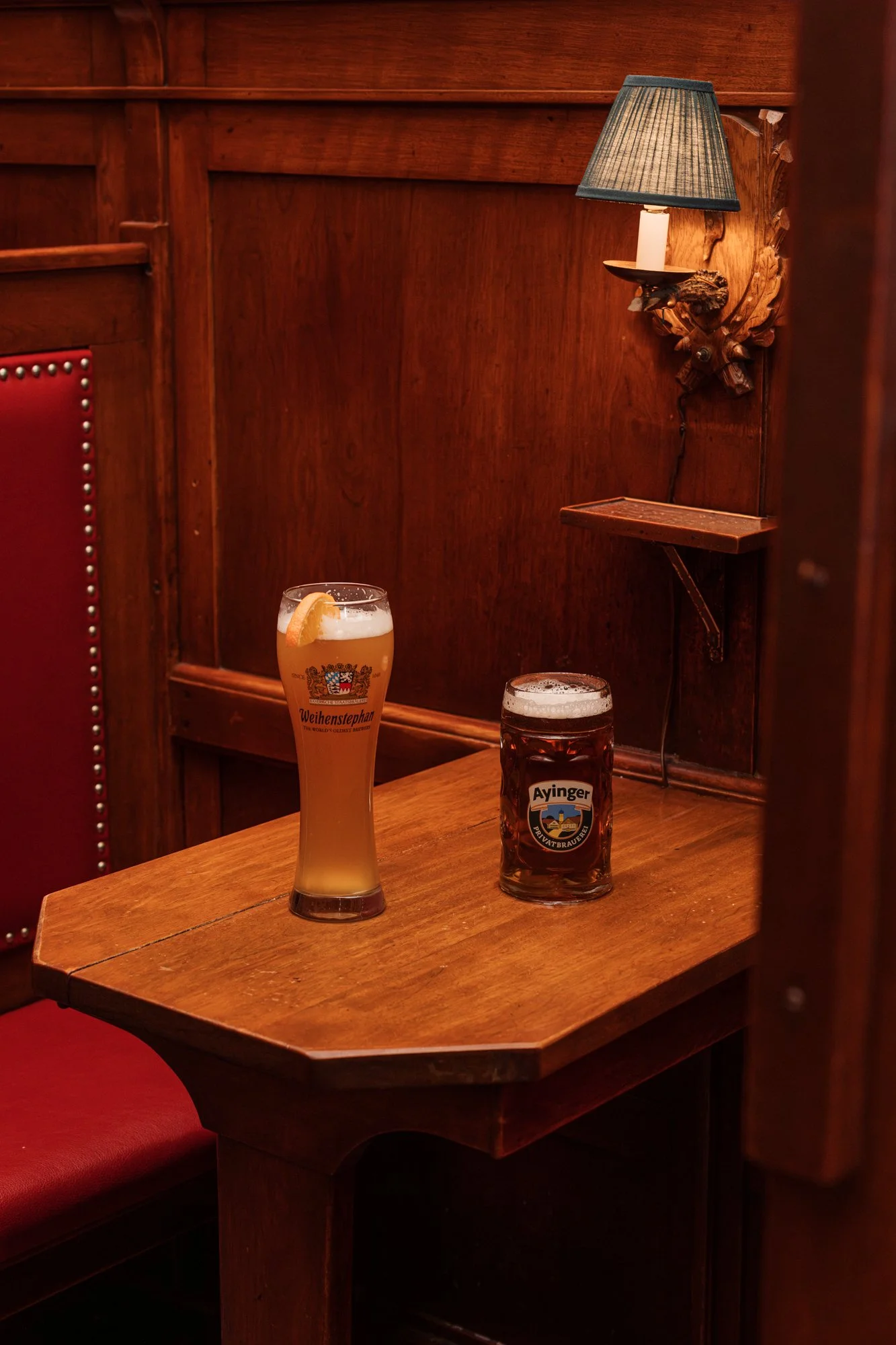 Two glasses of beer on a wooden table in a cozy, dimly lit bar with wood-paneled walls at The Student Prince in Springfield MA