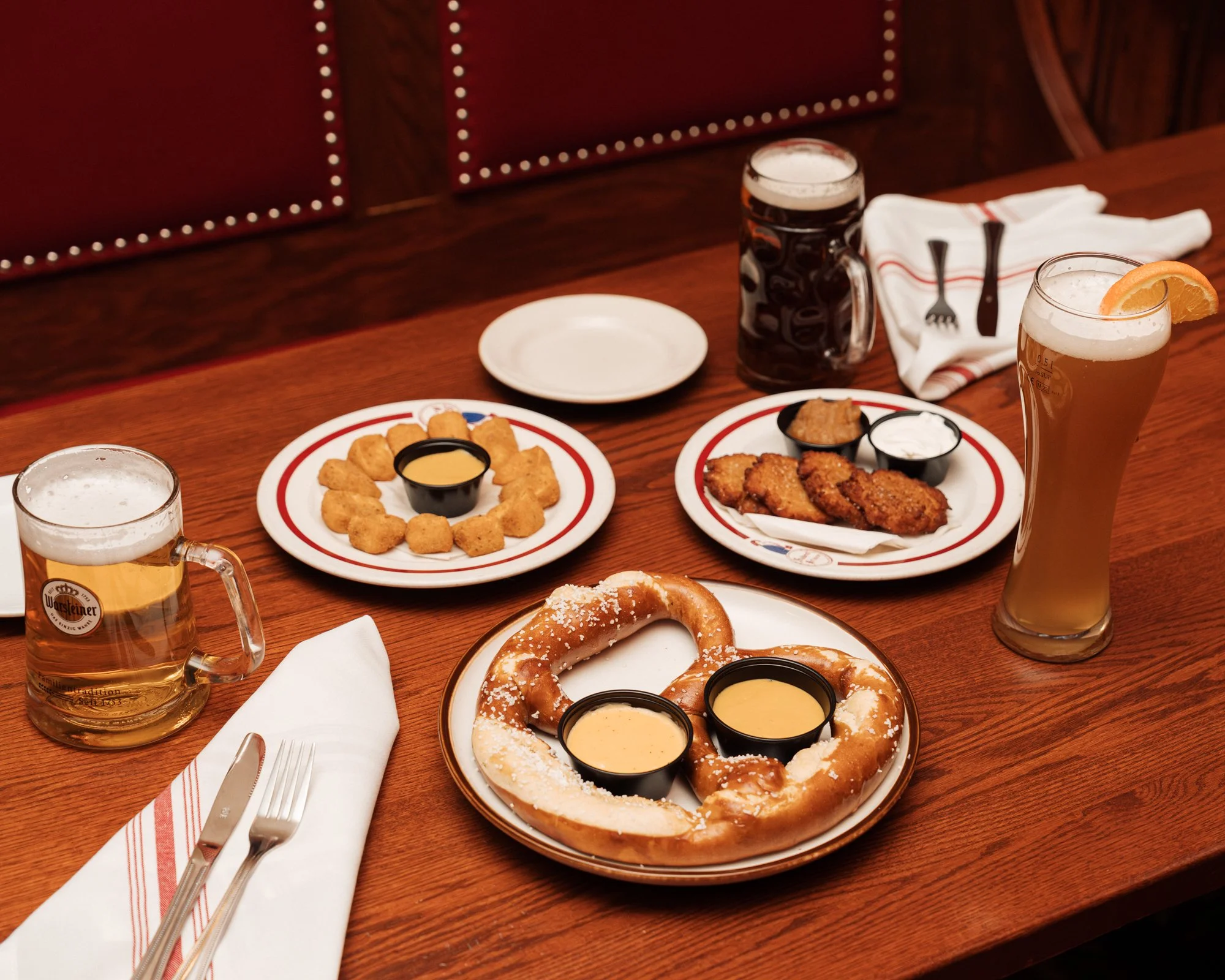Lightly fried butterflied shrimp with cocktail sauce, golden fried potato pancakes with apple sauce and sour cream, and our soft giant pretzel with beer cheese and honey mustard. Accompanied by two steins of beer and a pint of beer with a lemon