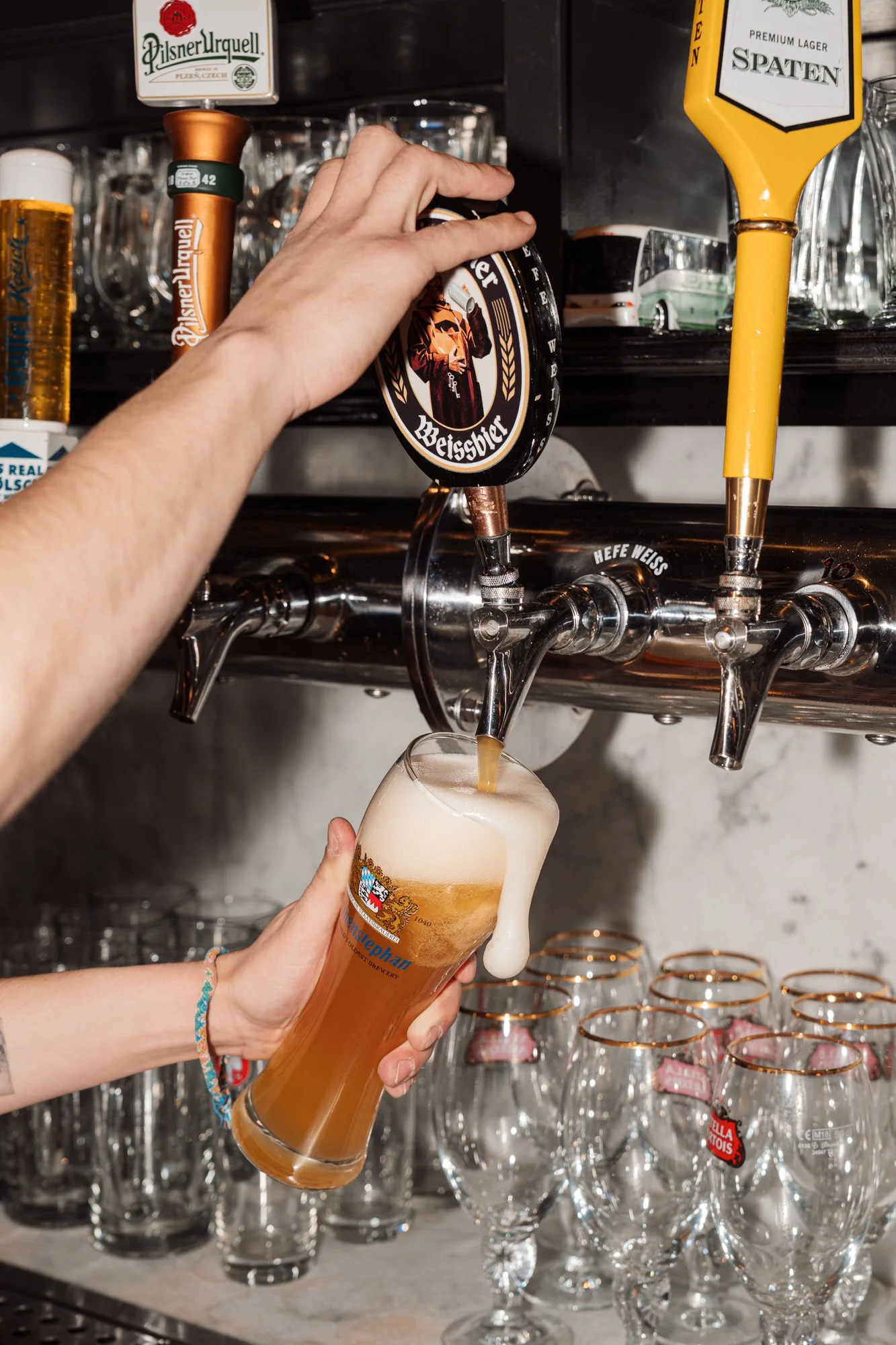 A person pours beer from a tap into a glass pint at a bar