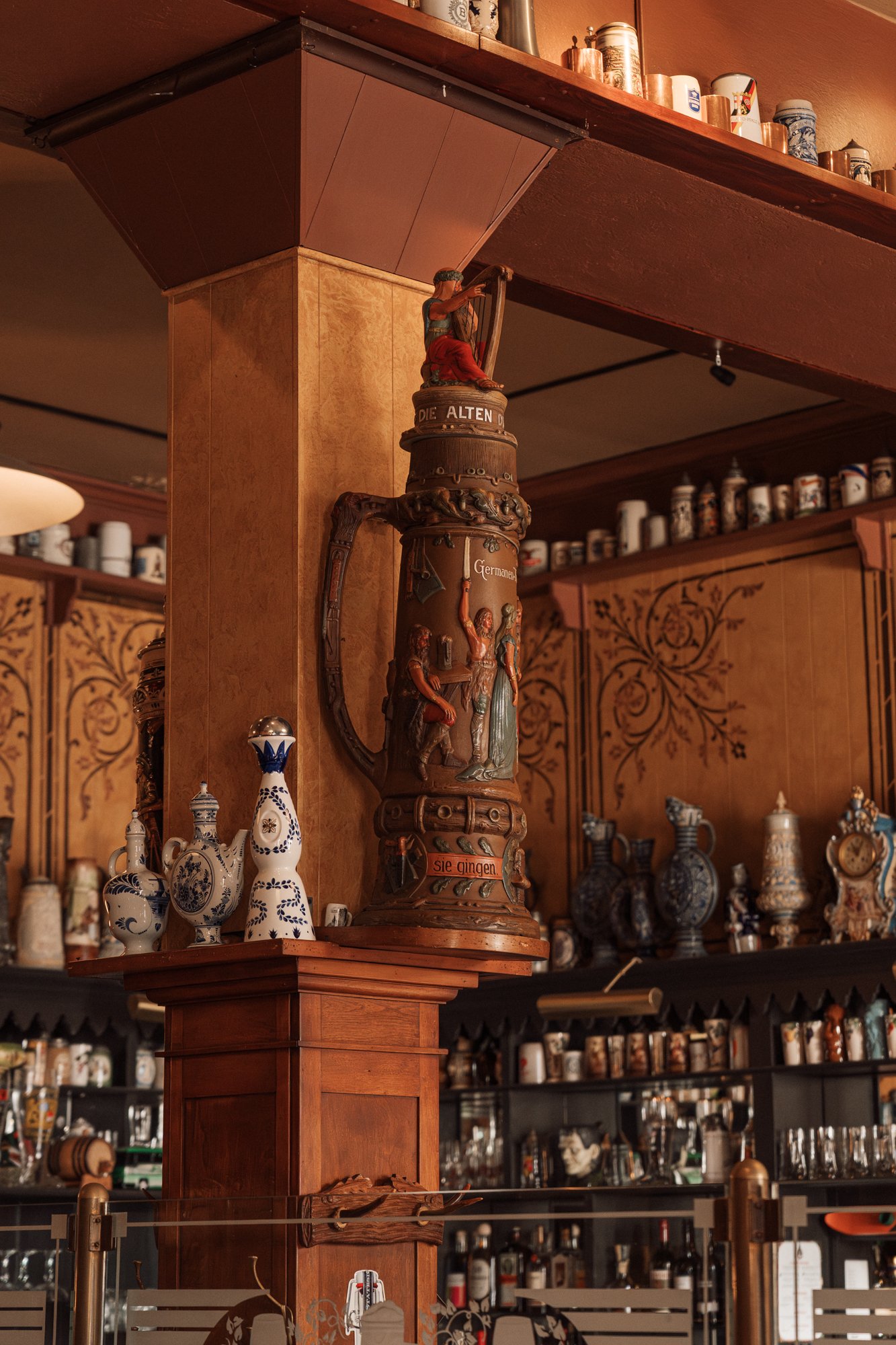 A collection of steins lining the top inside edge of the Student Prince Restaurant in Springfield MA, in a cozy, wood-paneled setting.