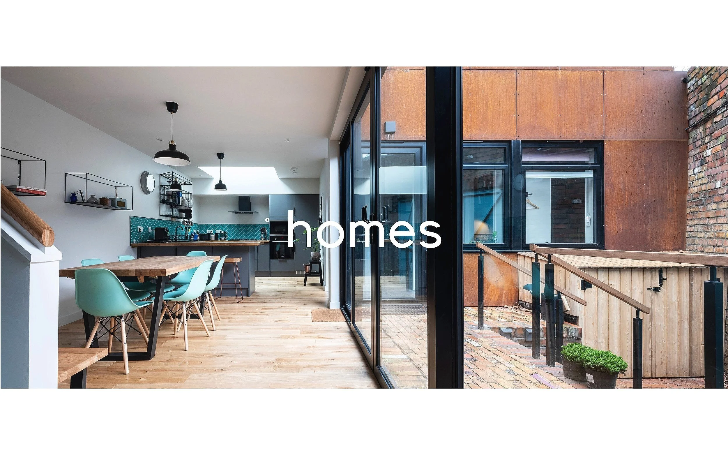 Barefoot Architects Ltd — Modern kitchen and dining area with large windows overlooking outdoor patio with brick and wooden steps.