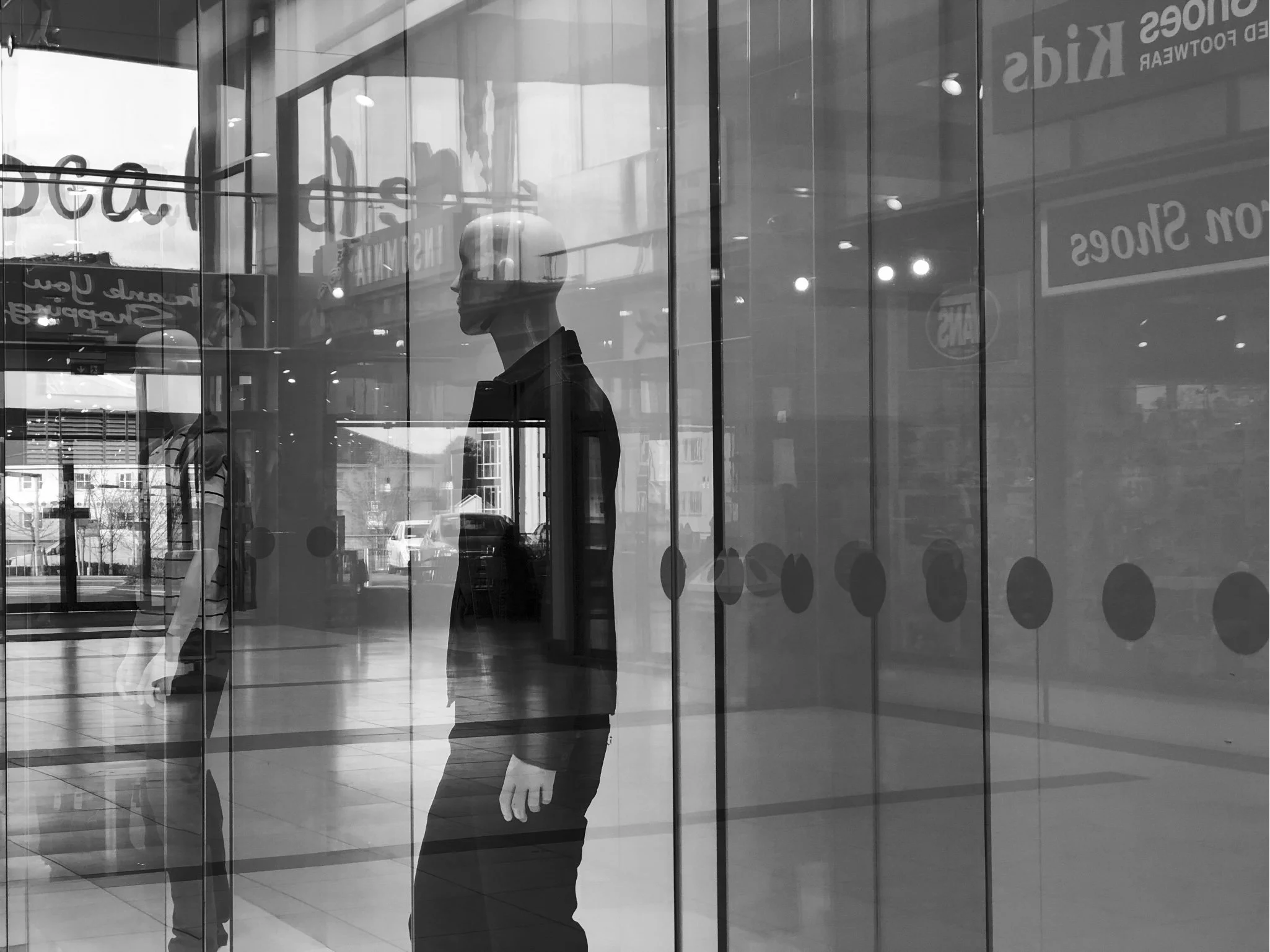 Image of an interior showing mannequin and various items reflected in the shop window