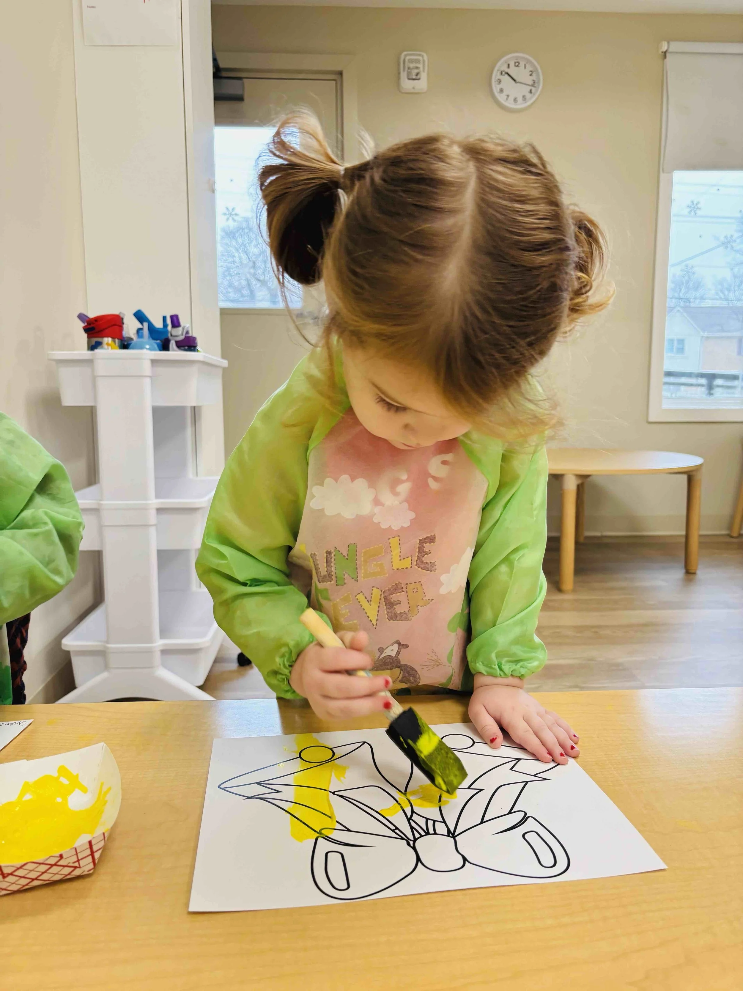 Toddler engaging in paint play as part of a developmentally appropriate childcare curriculum.