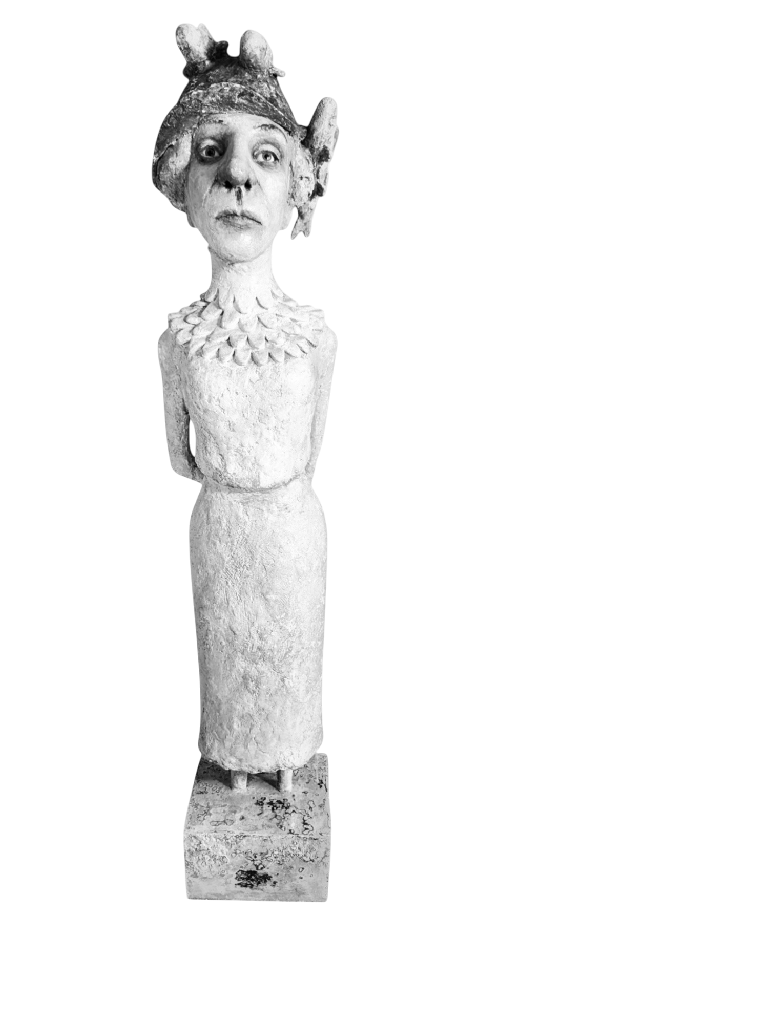 A stone sculpture of a woman with a human face, wearing a hat with animal ears and a colorful headscarf. The sculpture is mounted on a cylindrical base.